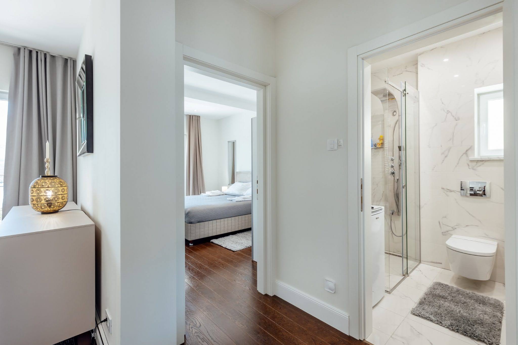 Innenraum eines Apartments in Kumbor, Montenegro: Blick auf ein modernes Schlafzimmer und ein Badezimmer mit heller Steinverkleidung.