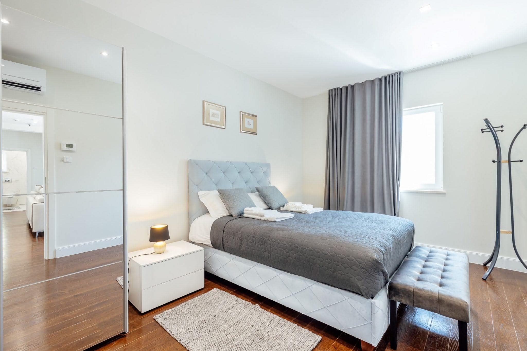 Modernes Schlafzimmer mit Doppelbett in einer Wohnanlage in Kumbor, Montenegro: helles Interieur, Parkett und Kleiderschrank mit Spiegeltüren.
