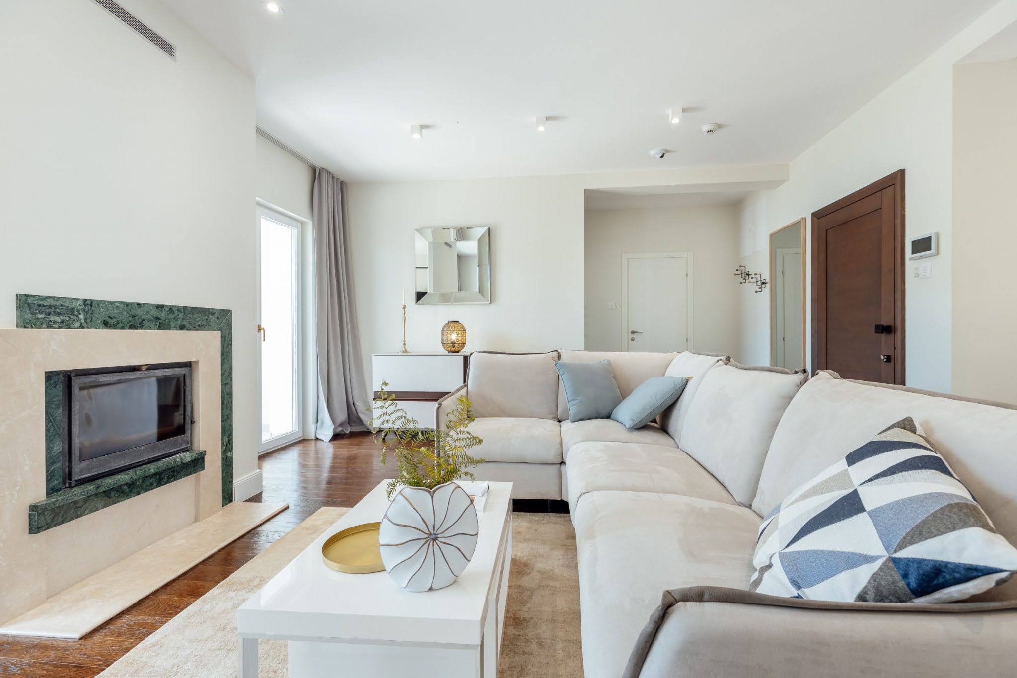 Helles Wohnzimmer mit Kamin und Ecksofa in einer Wohnanlage in Kumbor, Montenegro. Modernes Interieur.