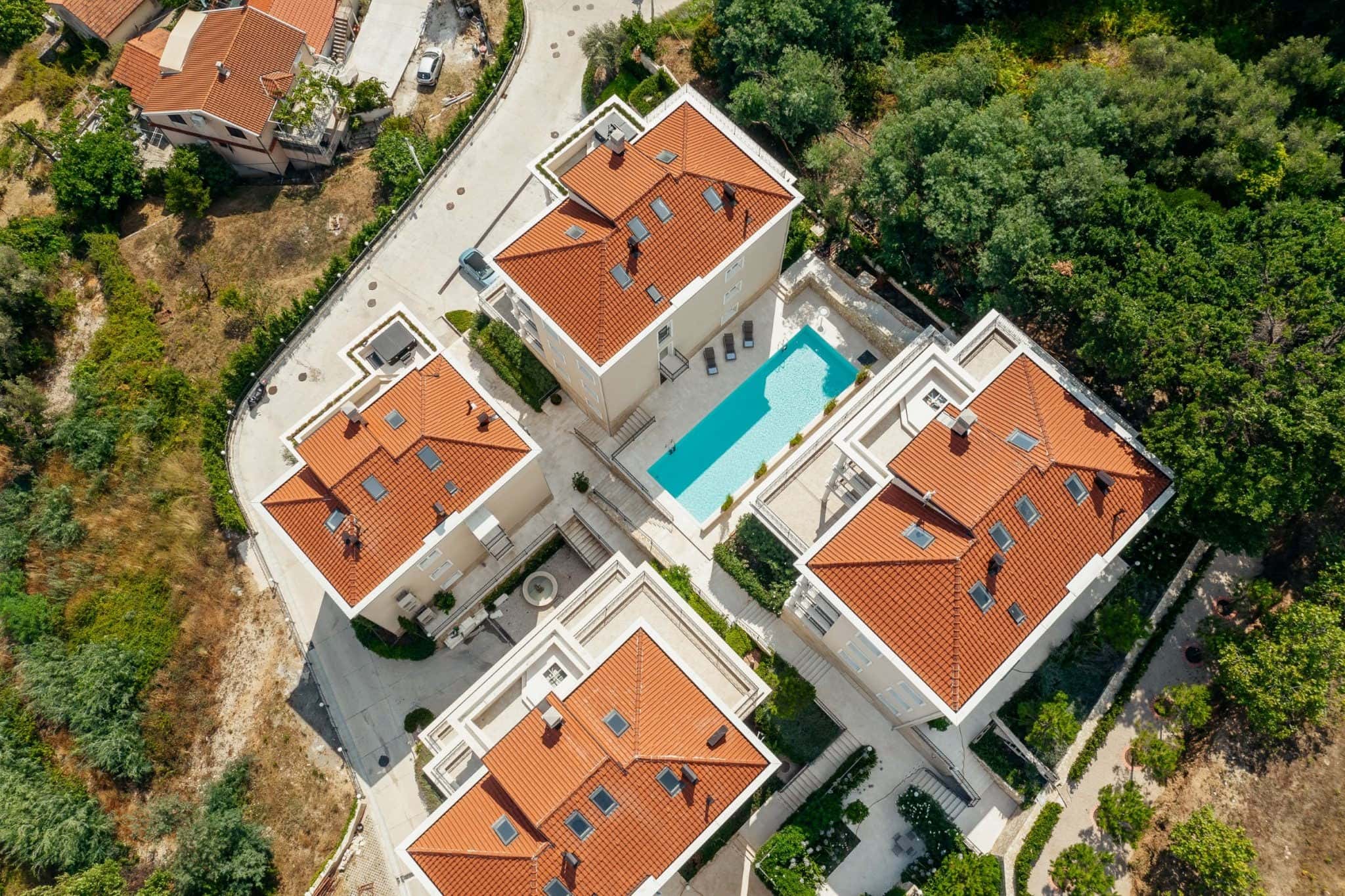 Blick von oben auf eine Wohnanlage in Kumbor, Montenegro: Villen mit roten Ziegeldächern, Pool und gepflegte Außenanlagen.