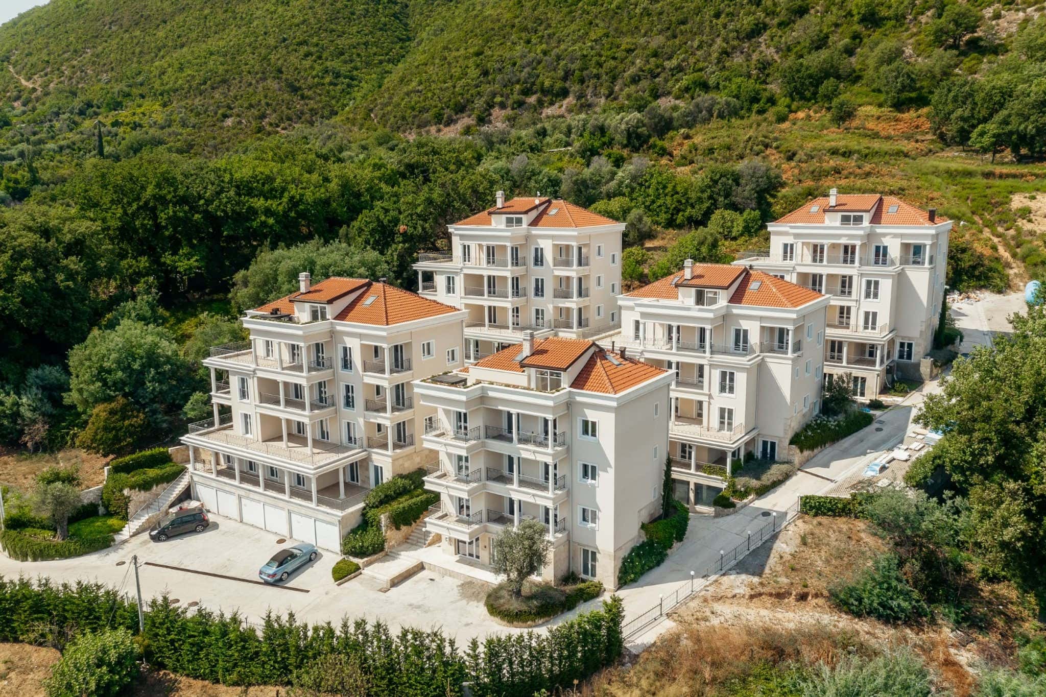 Wohnanlage in Kumbor, Montenegro: moderne Mehrfamilienhäuser mit Terrassen und Ziegeldächern in den Bergen.