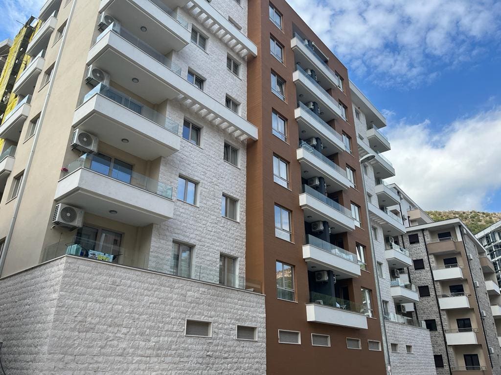 Moderner Wohnkomplex in Bečići, Montenegro: Fassade des Neubaus mit Balkonen, Panoramafenstern und Steinverkleidung.