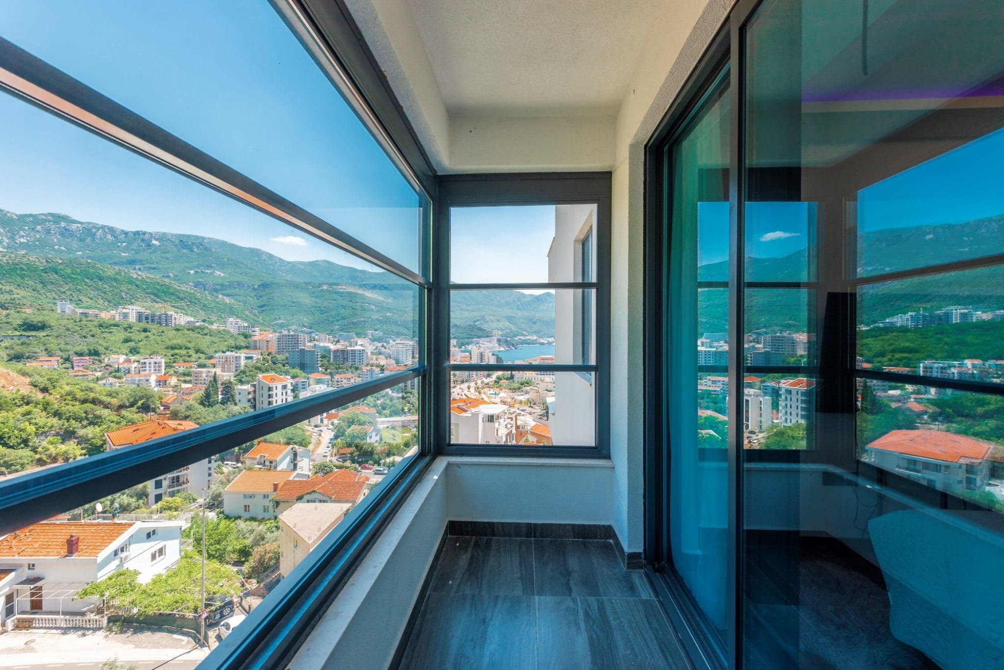 Panoramabalkon mit Blick auf das Meer und die Berge im Penthouse in Bečići, Montenegro: moderne Verglasung und Fliesen.