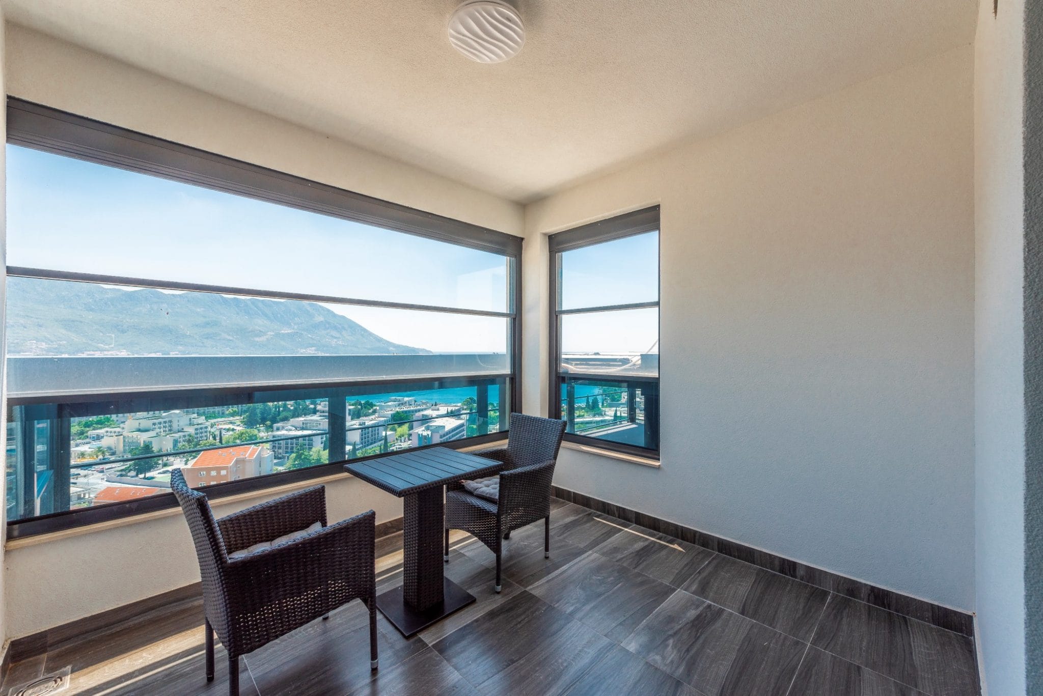Balkon des Penthouses in Bečići, Montenegro: Panoramablick auf das Meer, Rattanmöbel und Fliesenboden in einer modernen Wohnung.