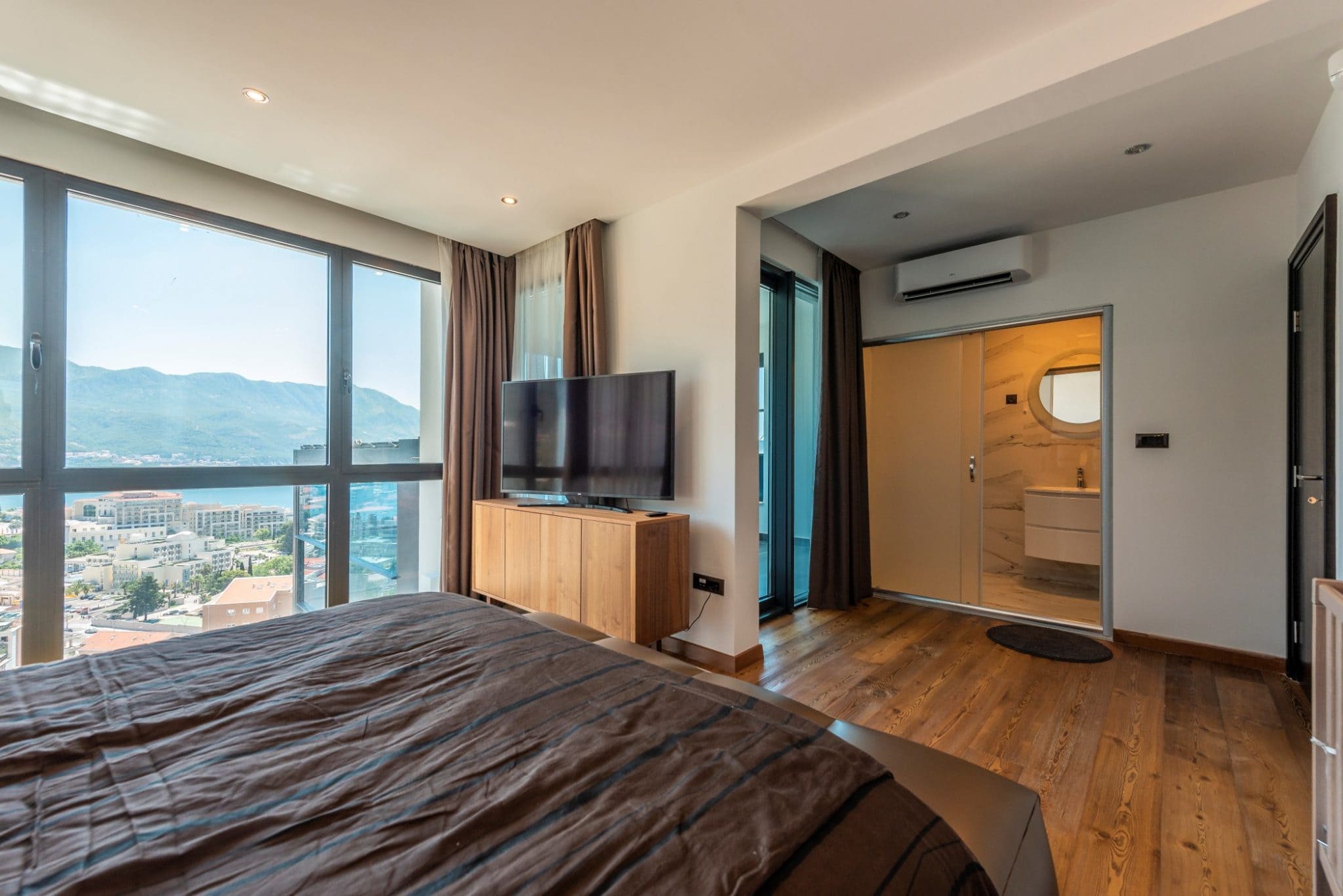 Schlafzimmer im Penthouse in Bečići, Montenegro: Panoramablick auf das Meer, moderne Möbel und ein eigenes Badezimmer.