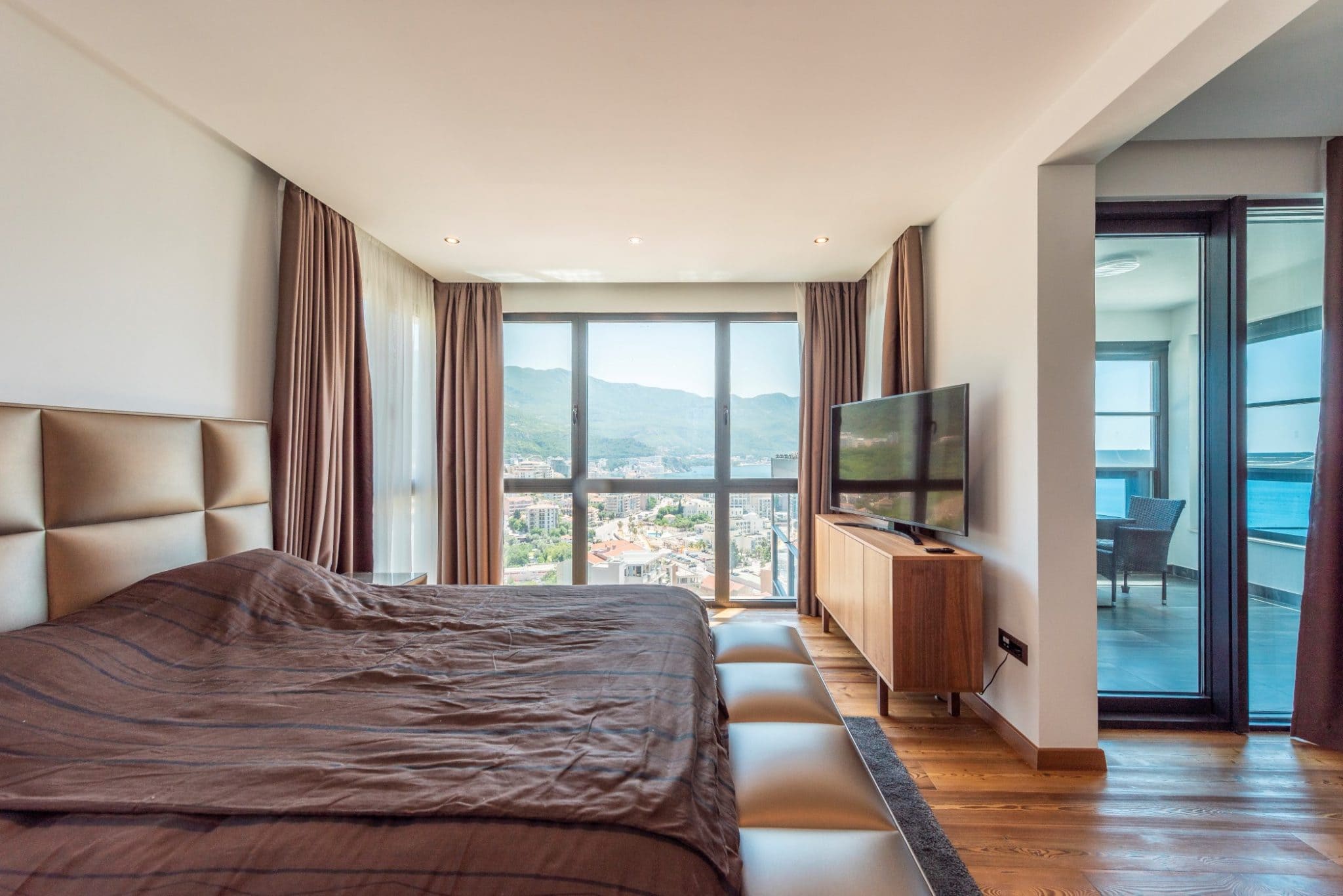 Schlafzimmer im Penthouse in Bečići, Montenegro: Panoramafenster mit Meerblick, Doppelbett und Zugang zur Terrasse.