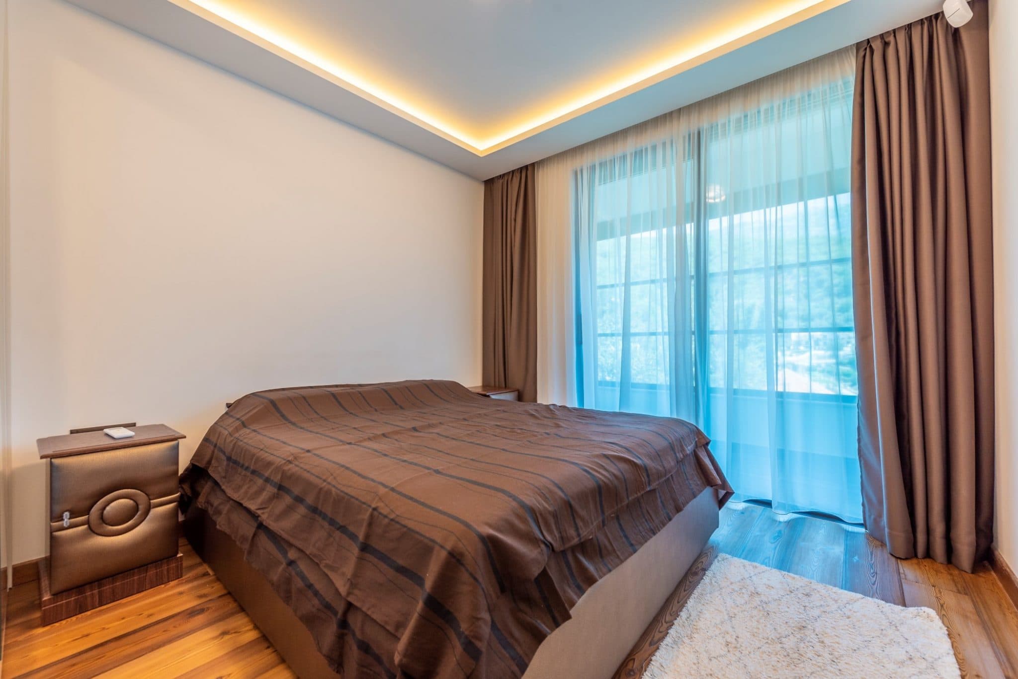 Modernes Schlafzimmer im Penthouse in Bečići, Montenegro: Doppelbett, Panoramafenster und stilvolle Beleuchtung.
