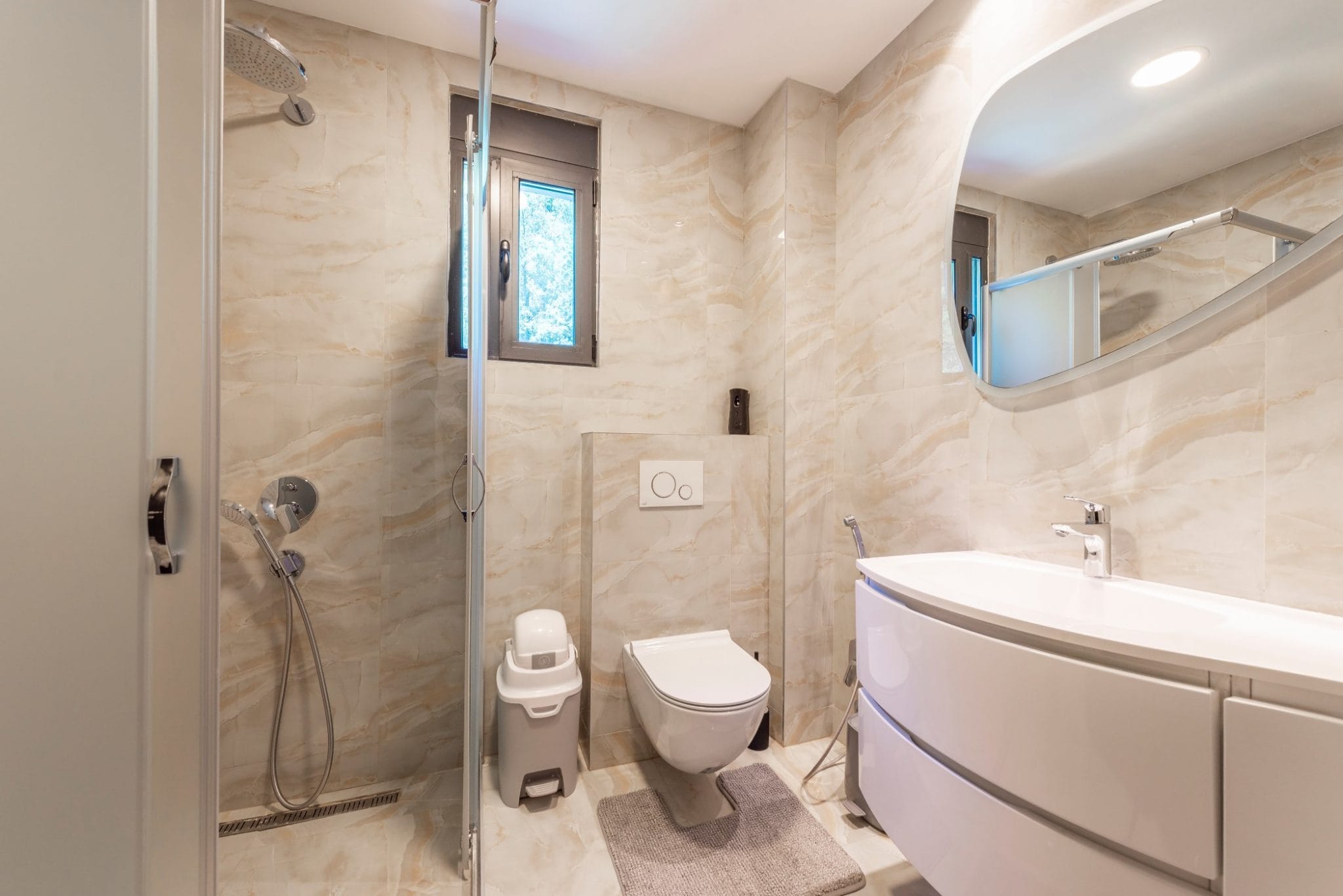 Modernes Badezimmer im Penthouse, Bečići, Montenegro: Duschkabine, wandhängendes WC und Waschtisch mit Waschbecken.