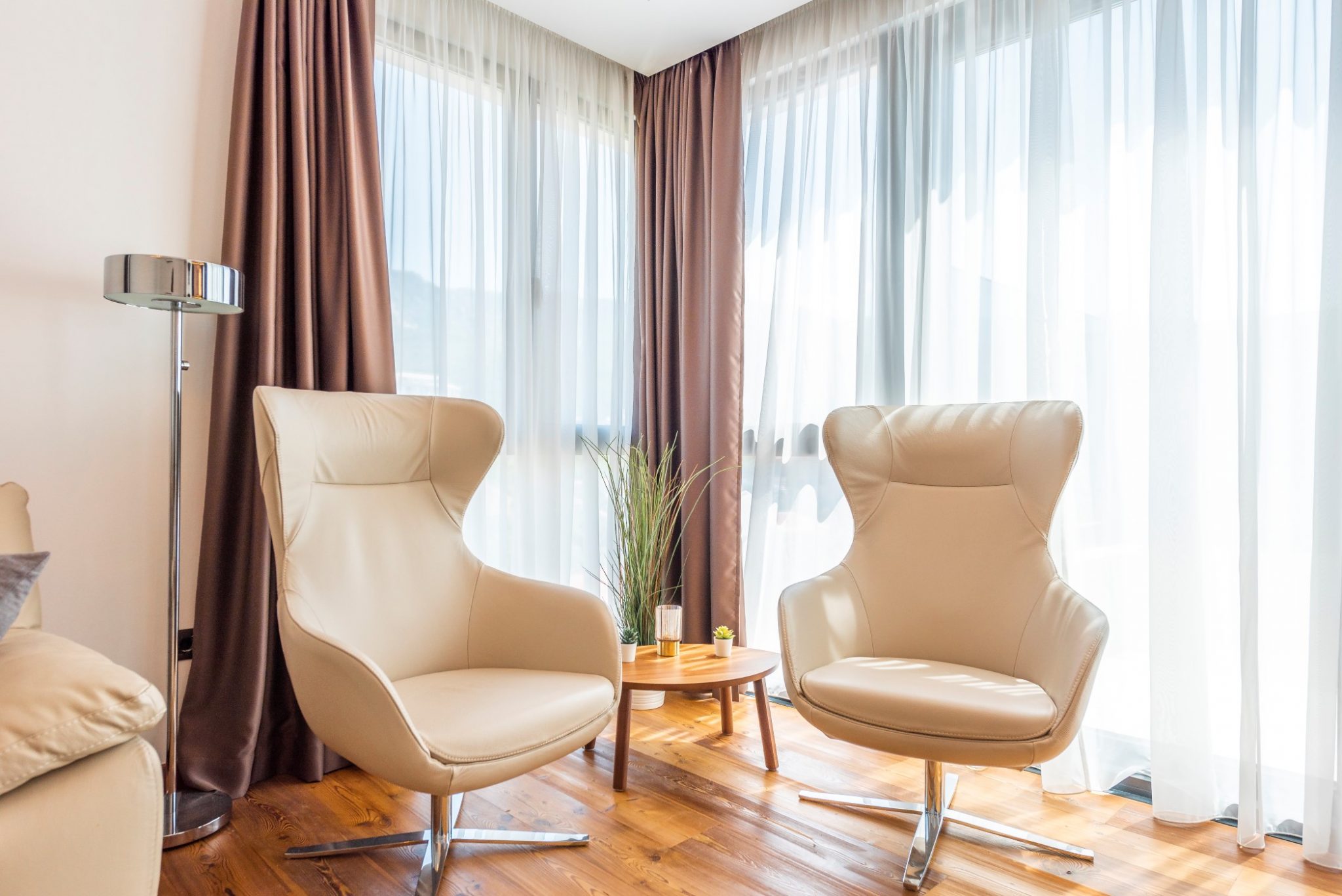 Zwei beige Sessel im Wohnzimmer eines Penthouses in Bečići, Montenegro, mit Panoramafenstern und Holzboden.