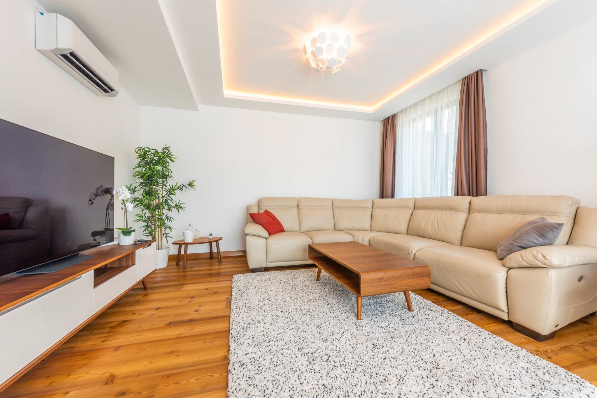 Modernes Wohnzimmer in einem Penthouse in Bečići, Montenegro: Ledersofa, Holzboden, TV-Bereich und stilvolle Beleuchtung.