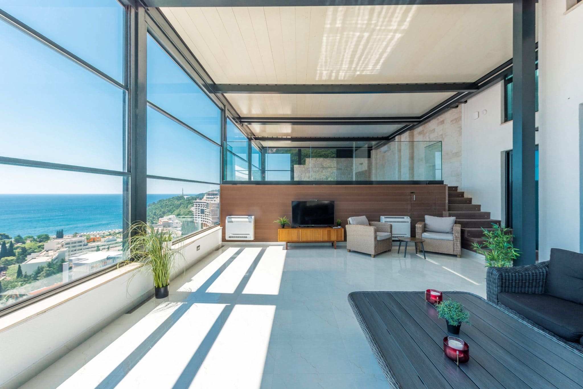 Wohnzimmer im Penthouse in Bečići, Montenegro: Panoramafenster mit Meerblick, moderne Möbel und Terrasse.