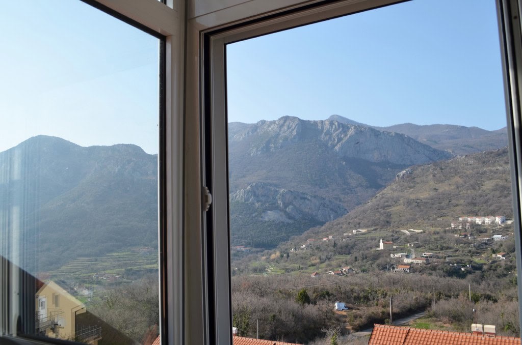 Karadağ’ın Bar şehrindeki dairede pencereden dağlar ve vadi manzarası: balkonundan panoramik manzara.