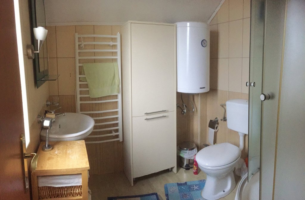 Bar, Karadağ’daki dairede banyo: duş kabini, бойler, dolap ve açık tonlarda sıhhi tesisat.