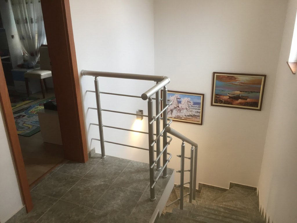 Karadağ’ın Bar şehrindeki iki katlı dairede, duvarlarda tablolar bulunan metal korkuluklu merdiven.