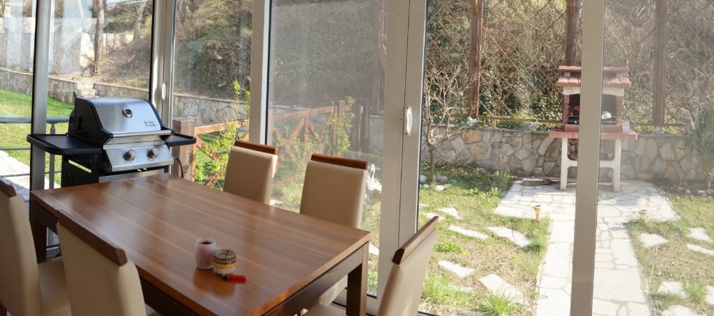 Bar, Karadağ’daki dairede yemek alanı ve barbekülü terasa çıkışı olan oturma odası.