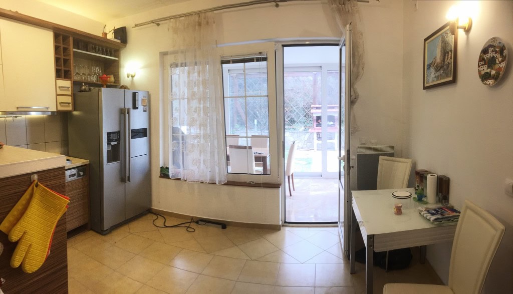 Bar, Karadağ’daki dairede yemek alanlı mutfak: açık renkli mobilyalar, terasa çıkış ve bahçe manzarası.