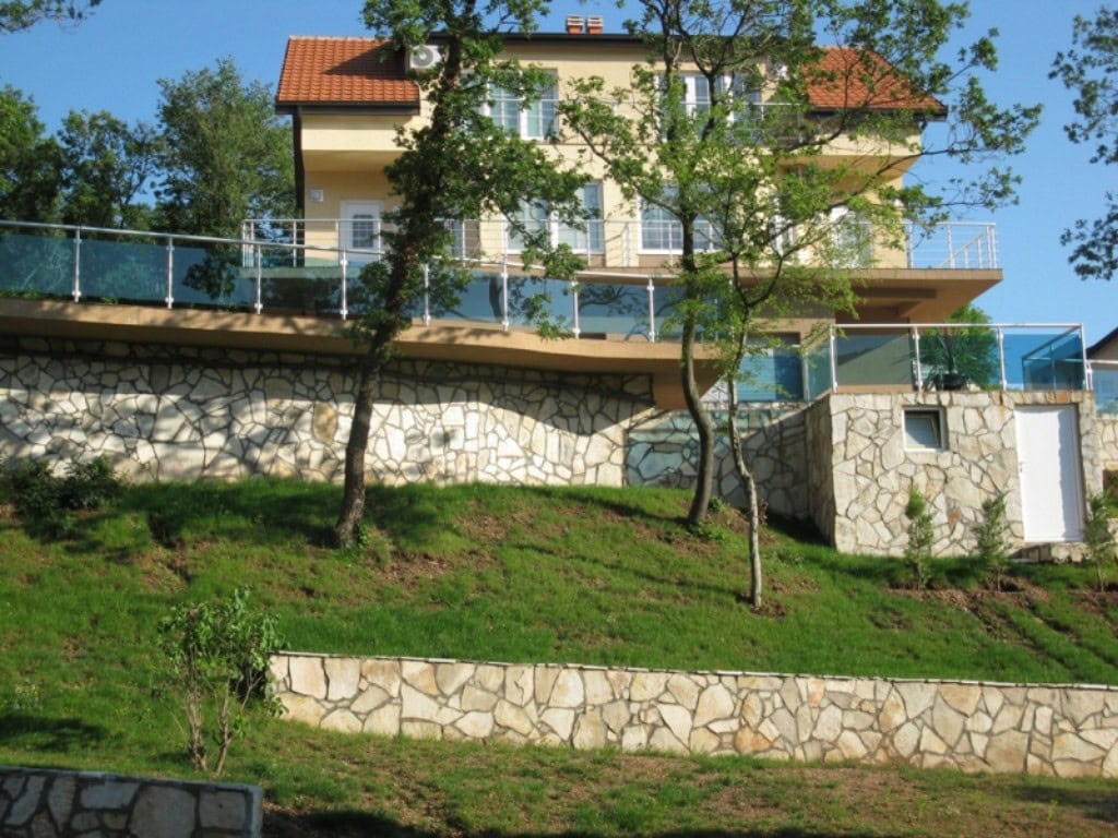 Karadağ, Bar şehrinde iki katlı ev: taş kaplamalı cephe, teraslar ve cam korkuluklar.
