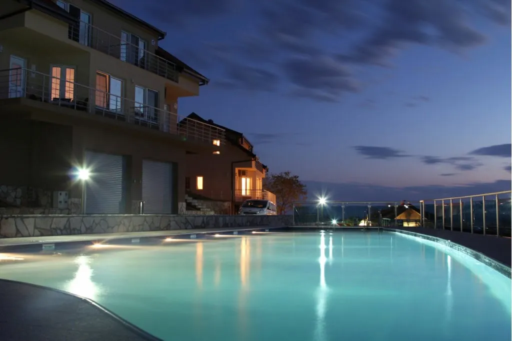 Abendlicher Pool mit Beleuchtung an einer modernen Villa in Bar, Montenegro, Blick auf Apartments mit Terrassen.
