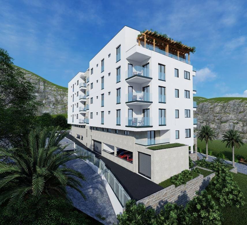 Modern residential complex in Budva, Montenegro: a white building with terraces, panoramic windows, and underground parking.