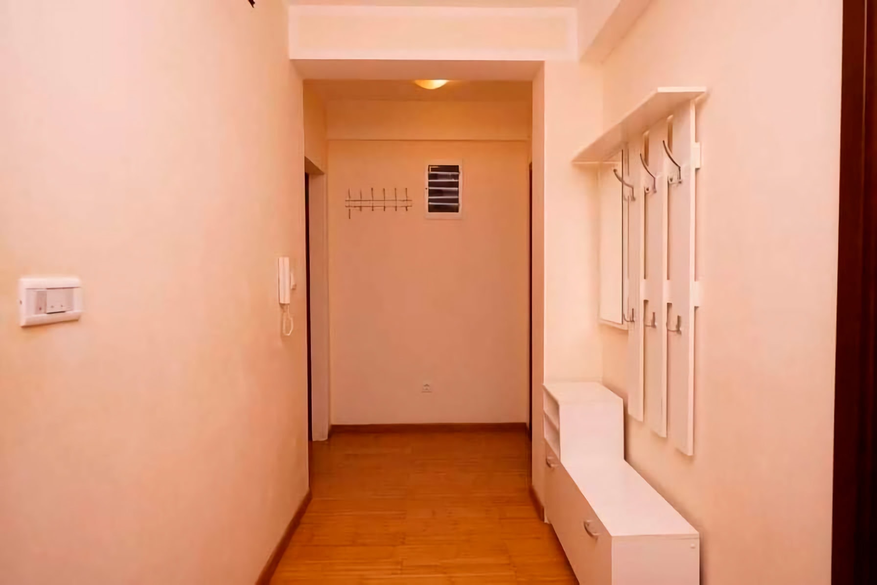 Helle Diele mit weißen Möbeln und Holzboden in einer zum Verkauf stehenden Wohnung in Budva, Montenegro.