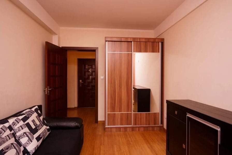 Wohnzimmer in einer Wohnung in Budva, Montenegro: Einbauschrank mit Spiegel, dunkles Sofa und Parkettboden im Interieur.