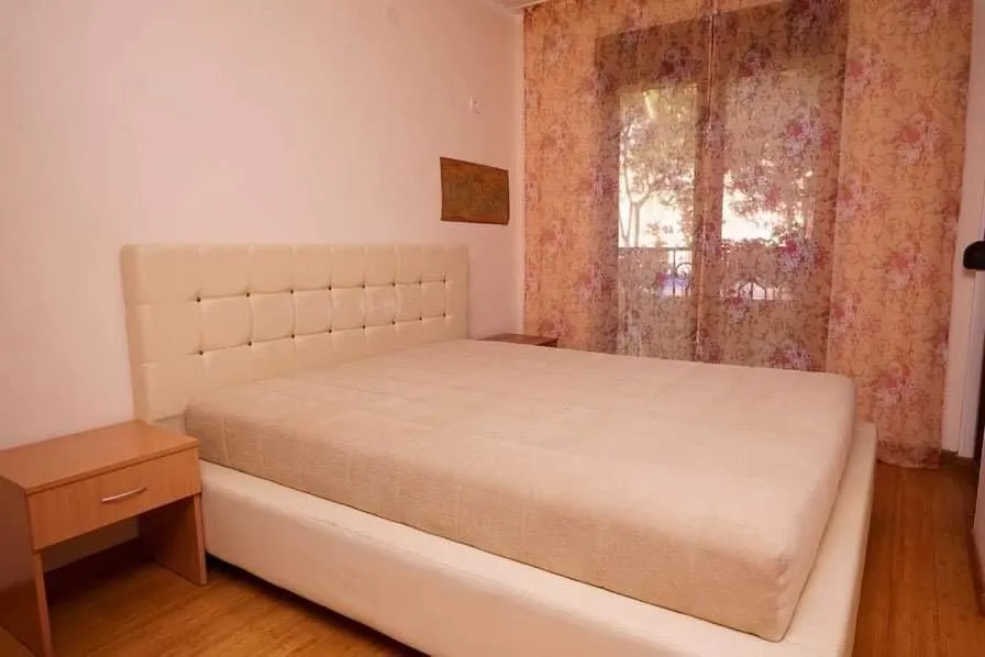 Udobna spavaća soba sa bračnim krevetom i izlazom na balkon u stanu u Budvi, Crna Gora.