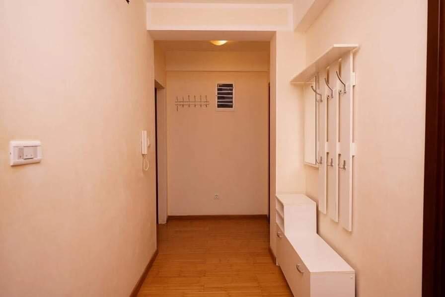 Heller Flur in einer Wohnung in Budva, Montenegro: weiße Möbel, Kleiderständer und Laminatboden.