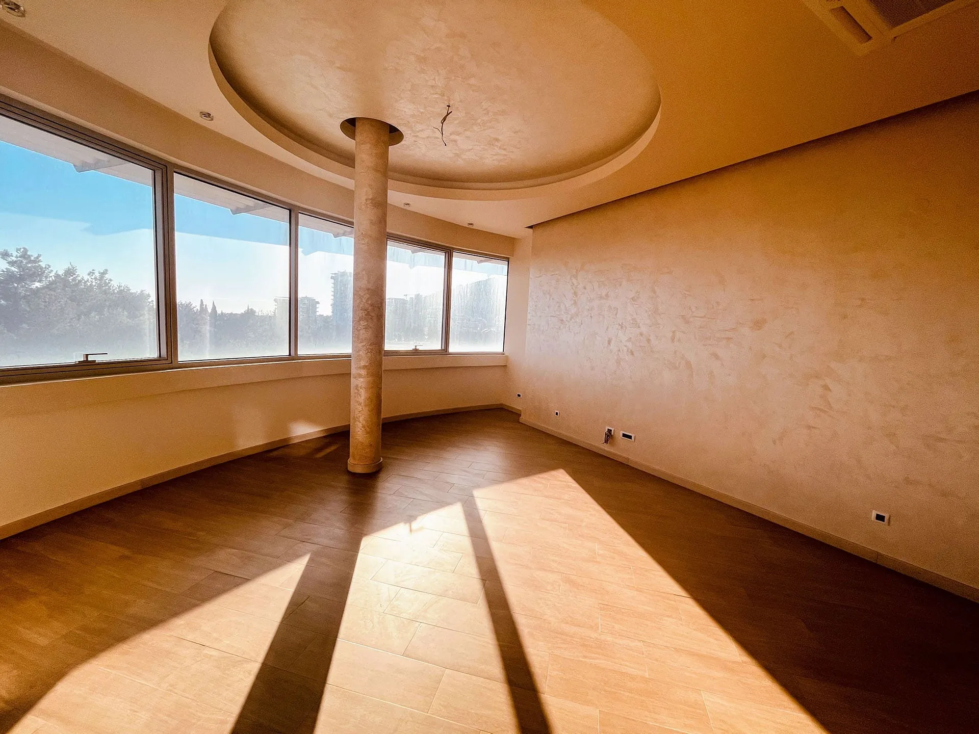 Helles Wohnzimmer in einer Wohnung in Budva, Montenegro: Panoramafenster, dekorative Säule und Wandgestaltung im Loft-Stil.