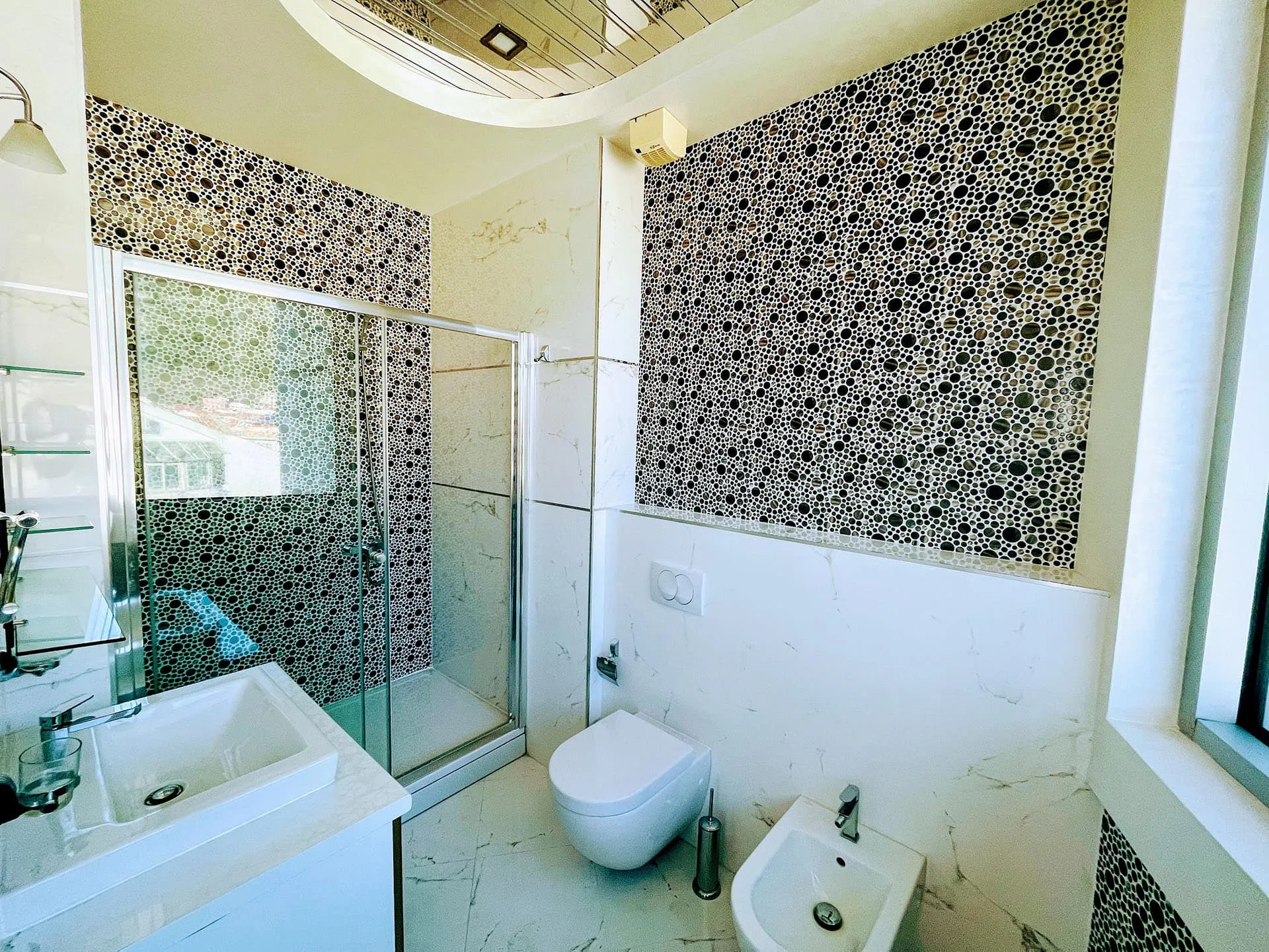 Modernes Badezimmer in einer Wohnung in Budva, Montenegro: Duschkabine, Mosaikfliesen und hochwertige Sanitäranlagen.