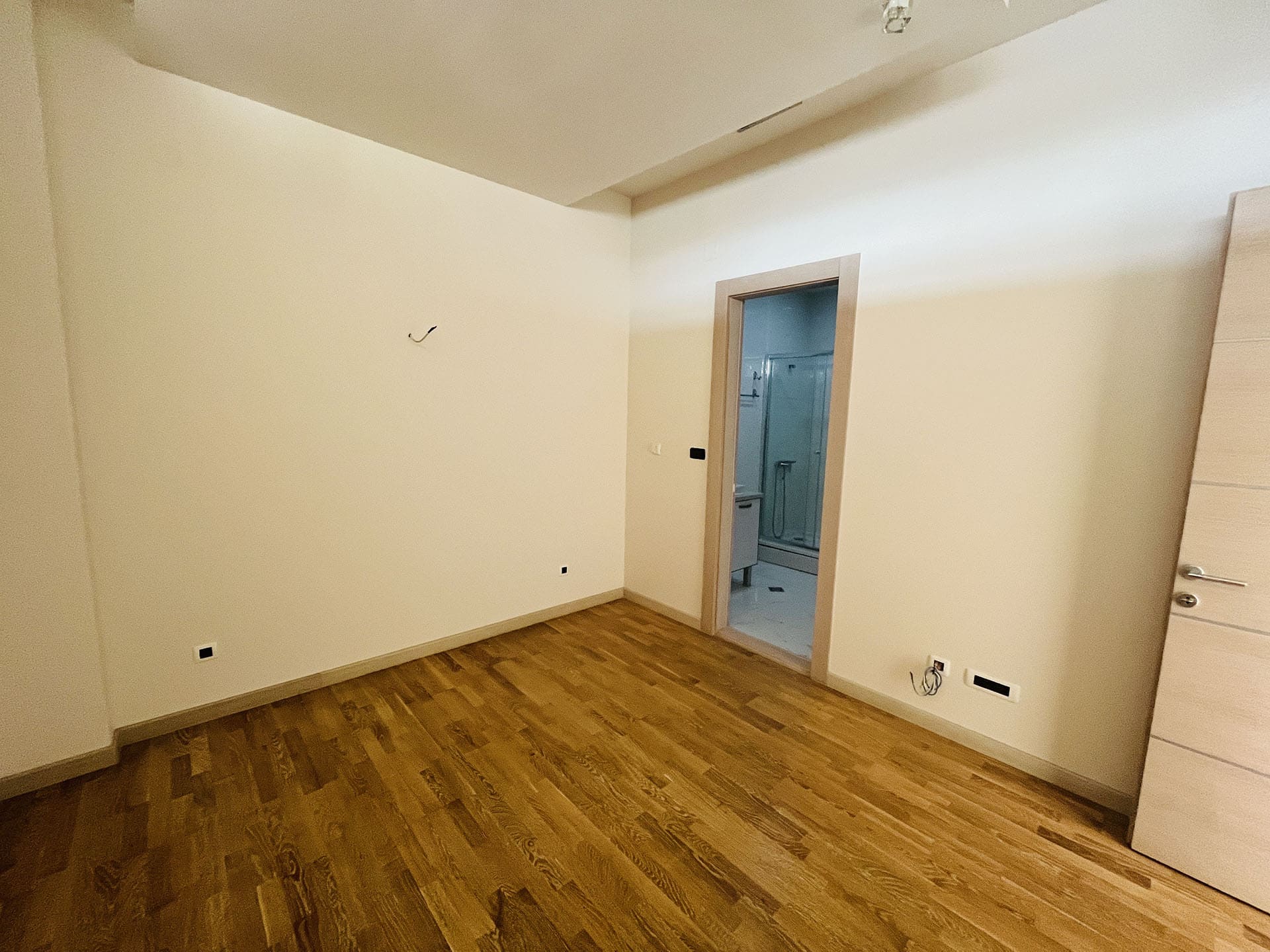 Helles Schlafzimmer mit Parkettboden und Zugang zum Badezimmer in einer Wohnung, Budva, Montenegro.