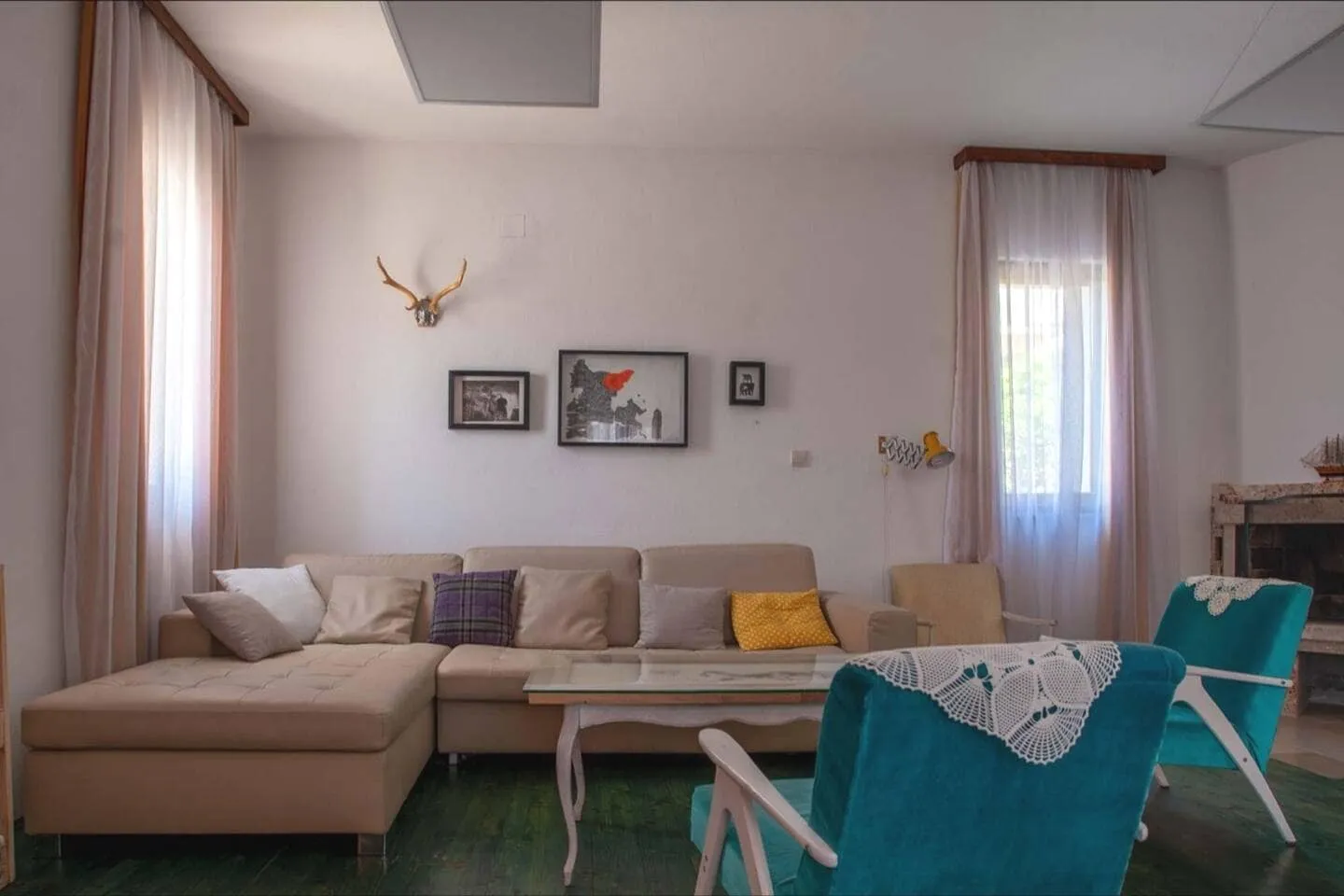 Cozy living room with a beige sofa and turquoise armchairs in a house, Shushan, Montenegro. Interior with a fireplace and decor.