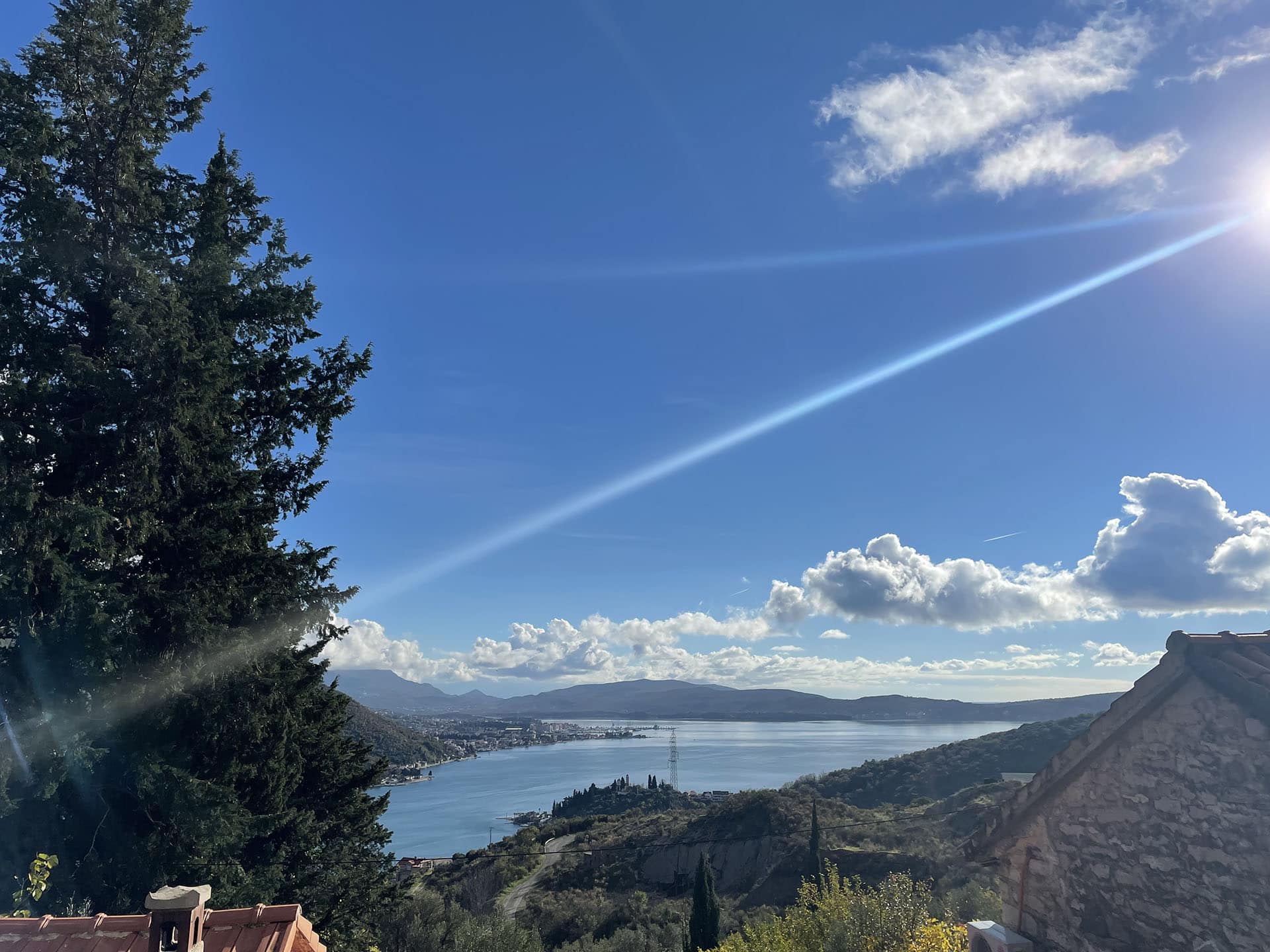 Vue panoramique sur la baie de Kotor et les montagnes depuis un terrain à Kamenari, Monténégro, par une journée ensoleillée.