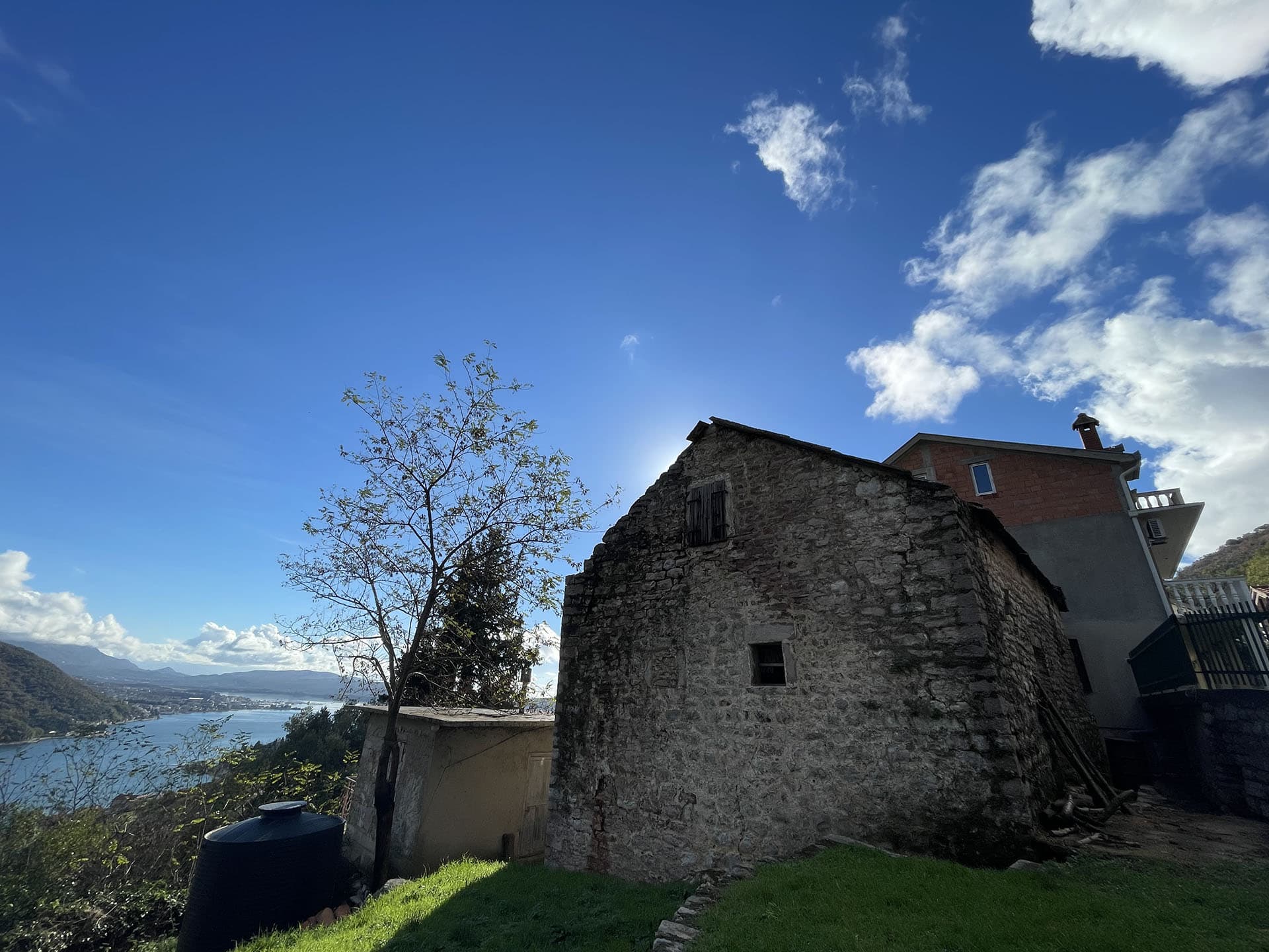 Ancienne maison en pierre sur un terrain à Kamenari, Monténégro, avec vue panoramique sur la baie de Kotor et les montagnes.