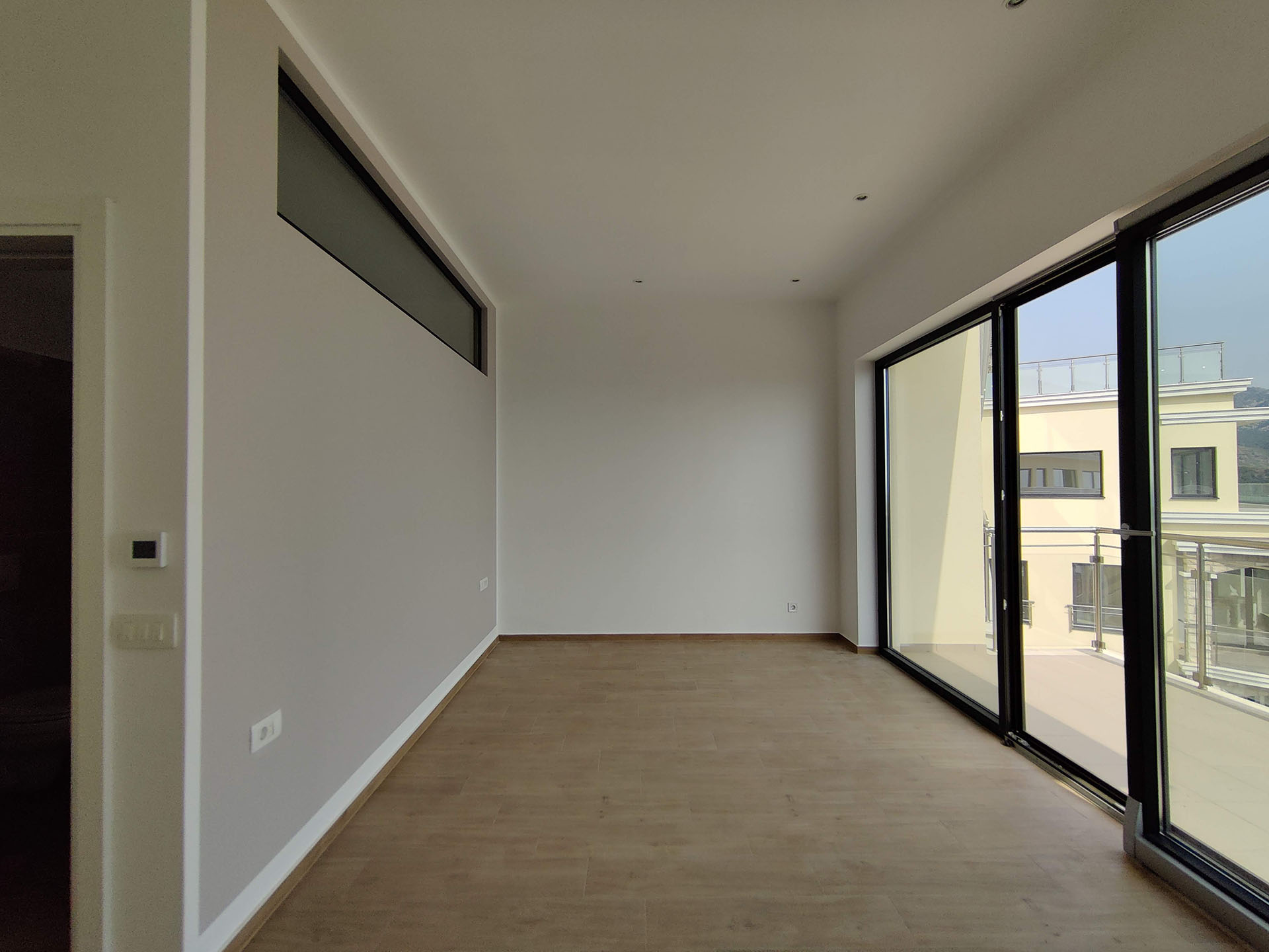 Bright living room in a new apartment in Becici, Montenegro: panoramic windows, access to the terrace, and modern finishes.
