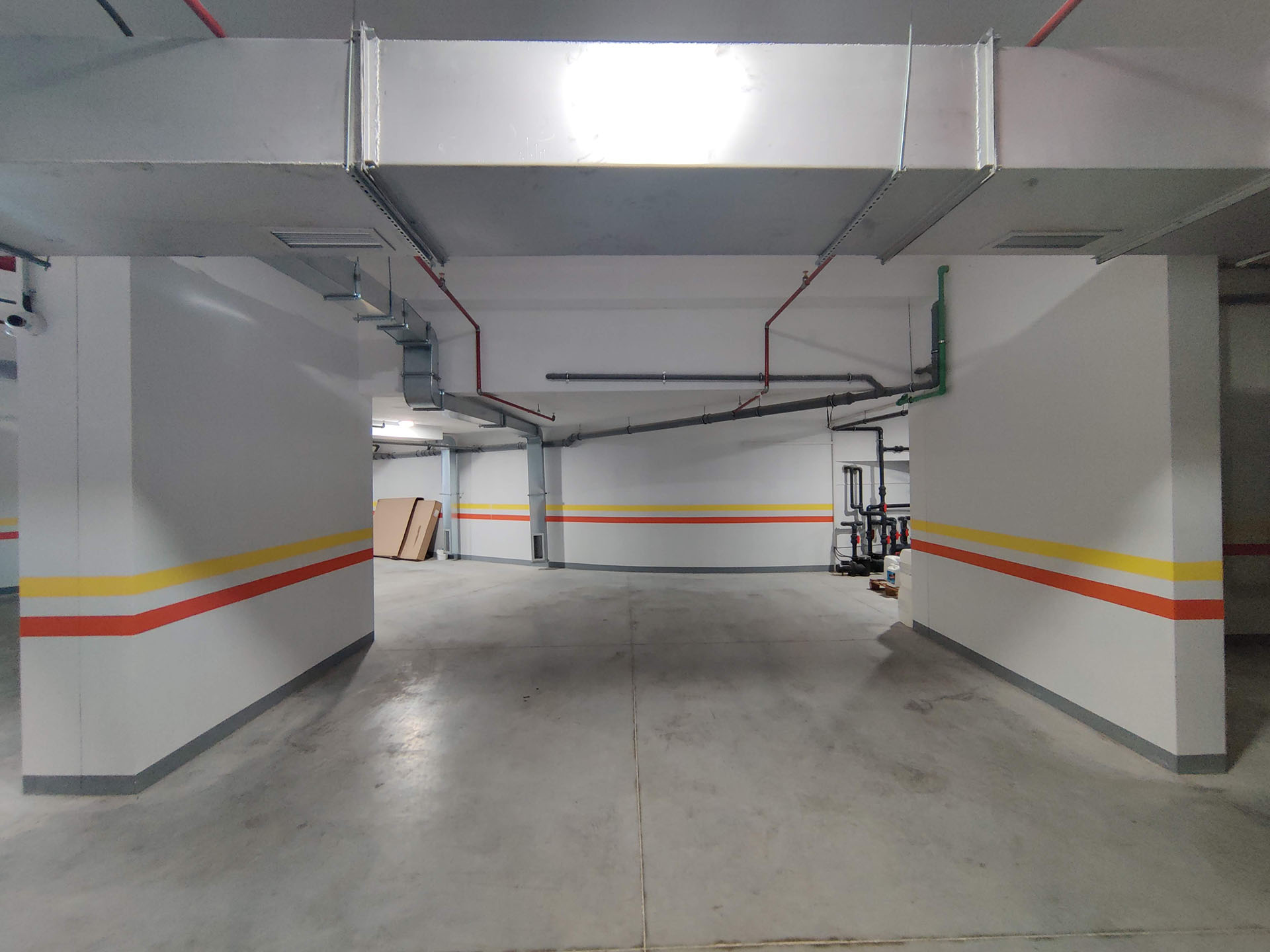 Underground parking in a residential complex in Bečići, Montenegro: concrete floor, lighting, and technical utilities.