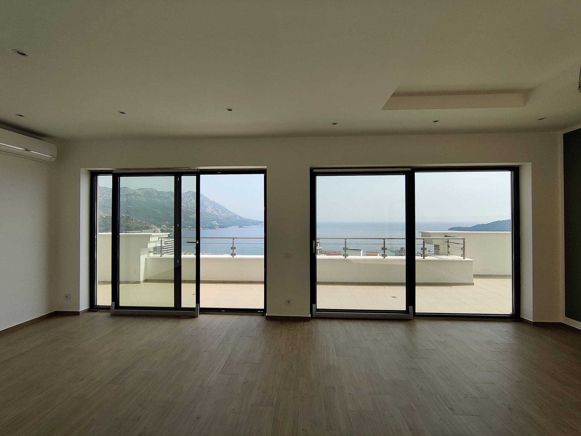 Living room with panoramic windows and sea view in an apartment, Becici, Montenegro: bright interior with access to the terrace.