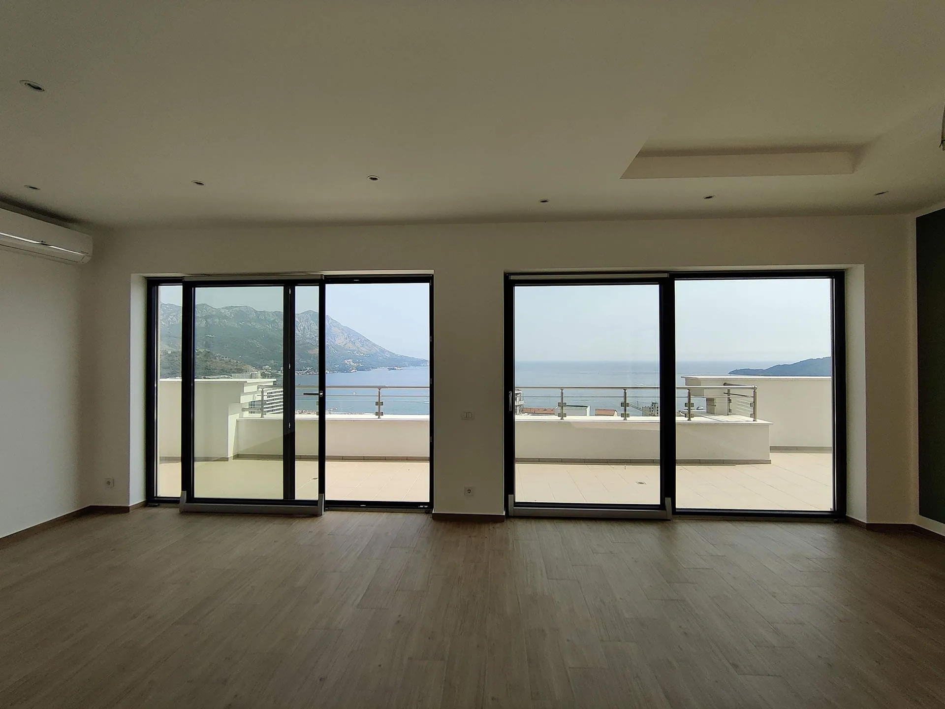 Wohnzimmer mit Panoramafenstern und Meerblick in einer Wohnung, Bečići, Montenegro: helles Interieur mit Zugang zur Terrasse.