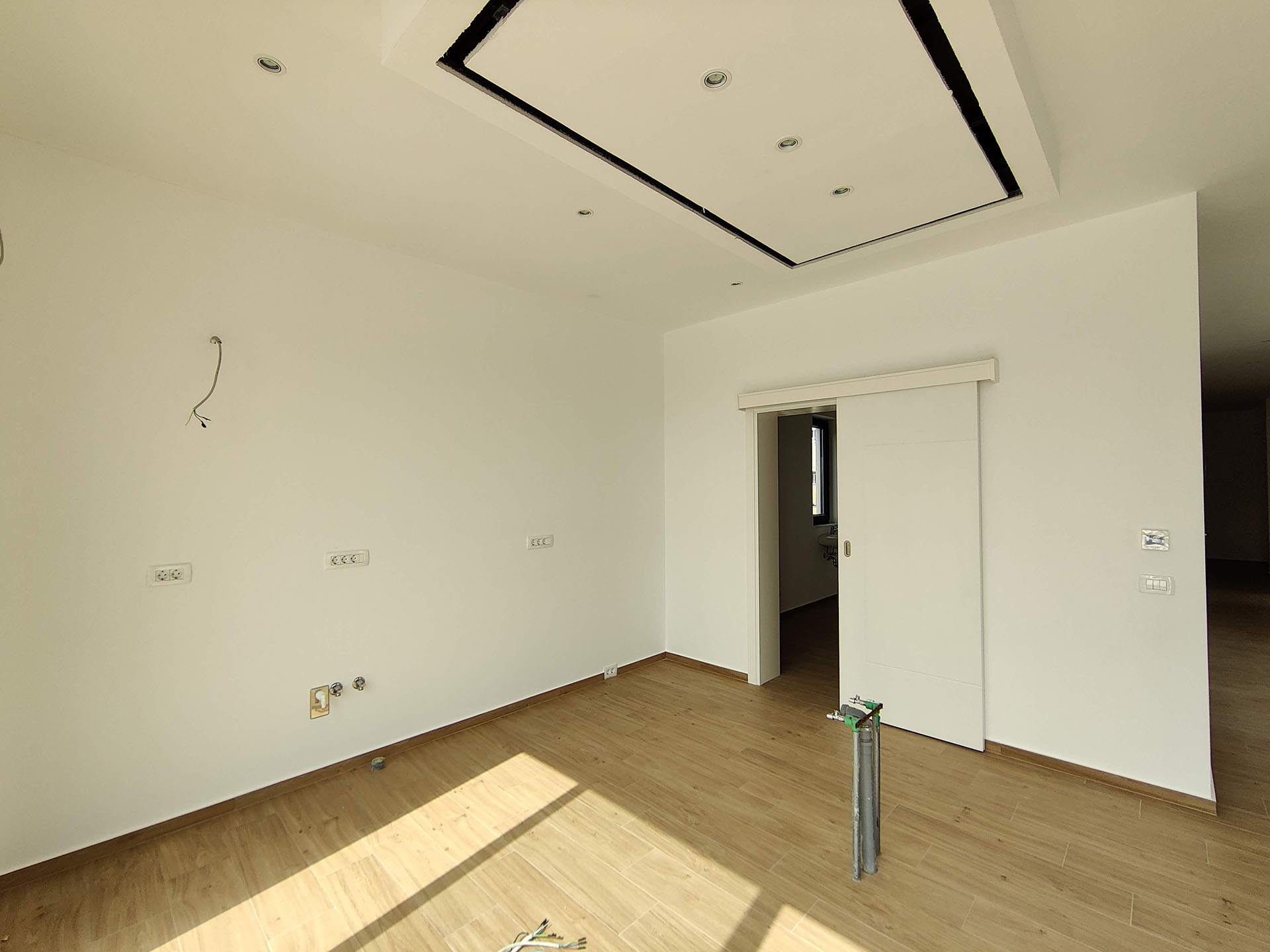 Bright living room in a new apartment in Bečići, Montenegro: modern finishes, sliding door, and recessed lighting.