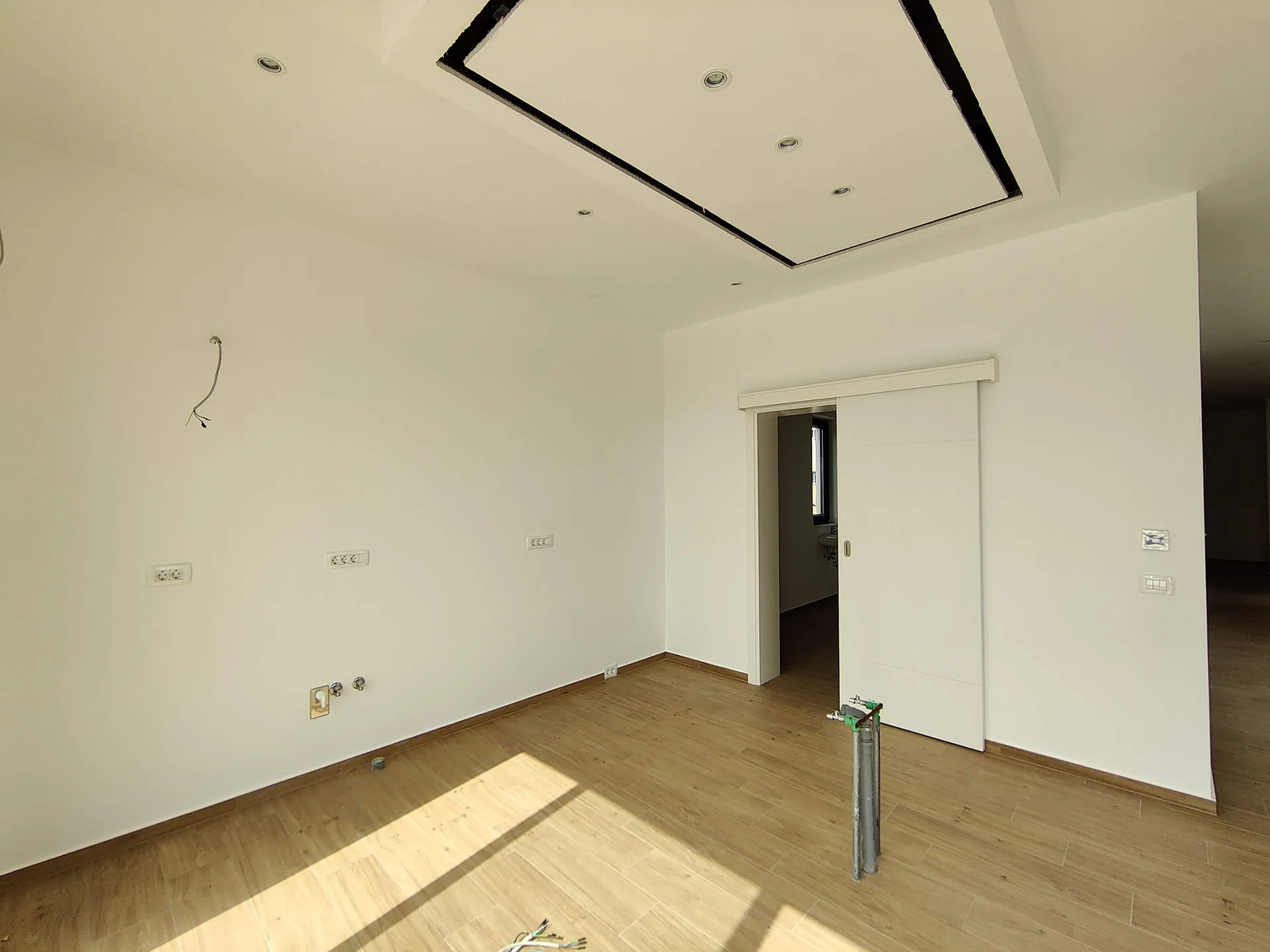 Helles Wohnzimmer in einer neuen Wohnung in Bečići, Montenegro: moderne Ausstattung, Schiebetür und Spotbeleuchtung.