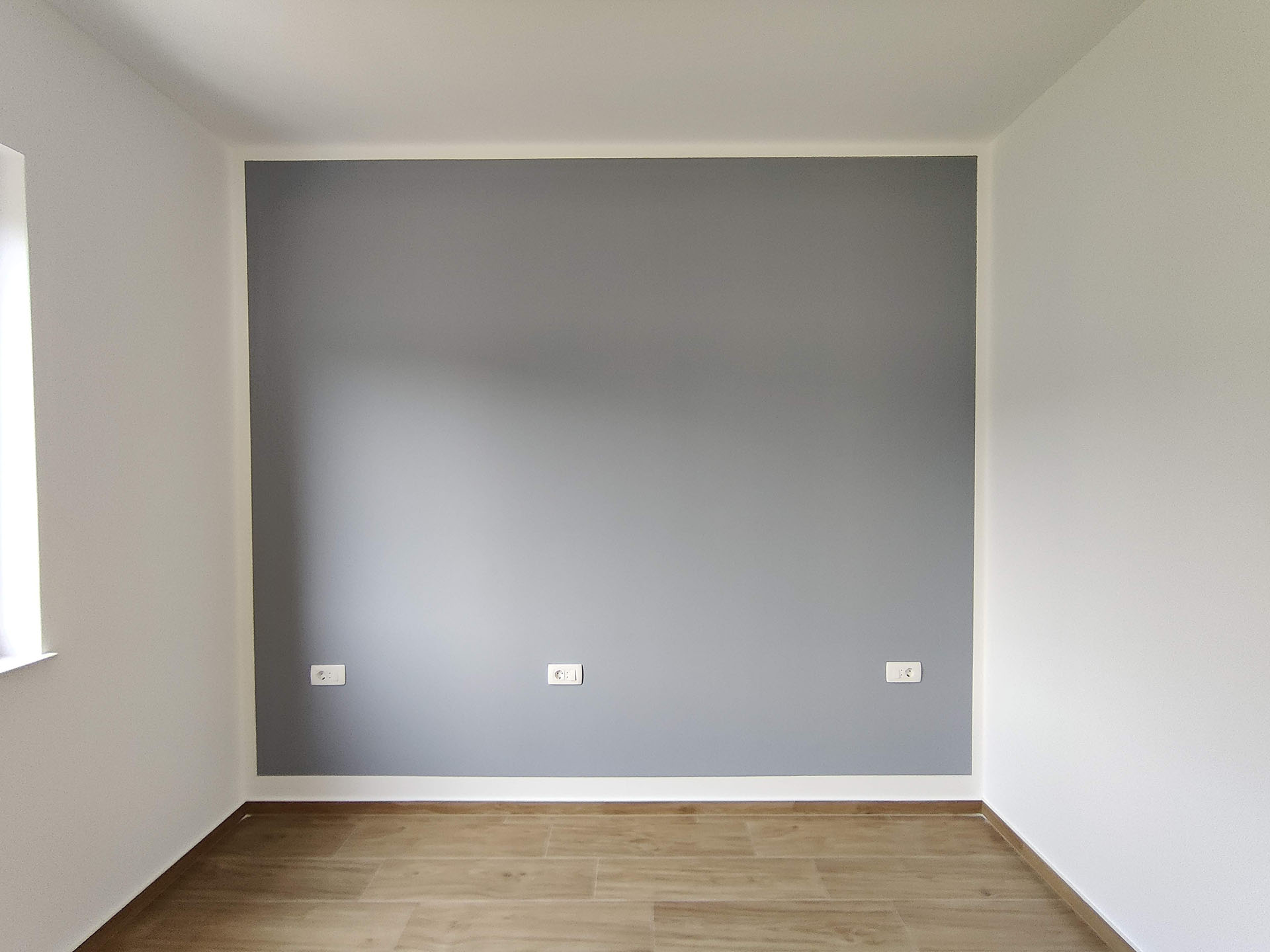 Bright bedroom with a gray accent wall and wooden floor in an apartment in Bečići, Montenegro.