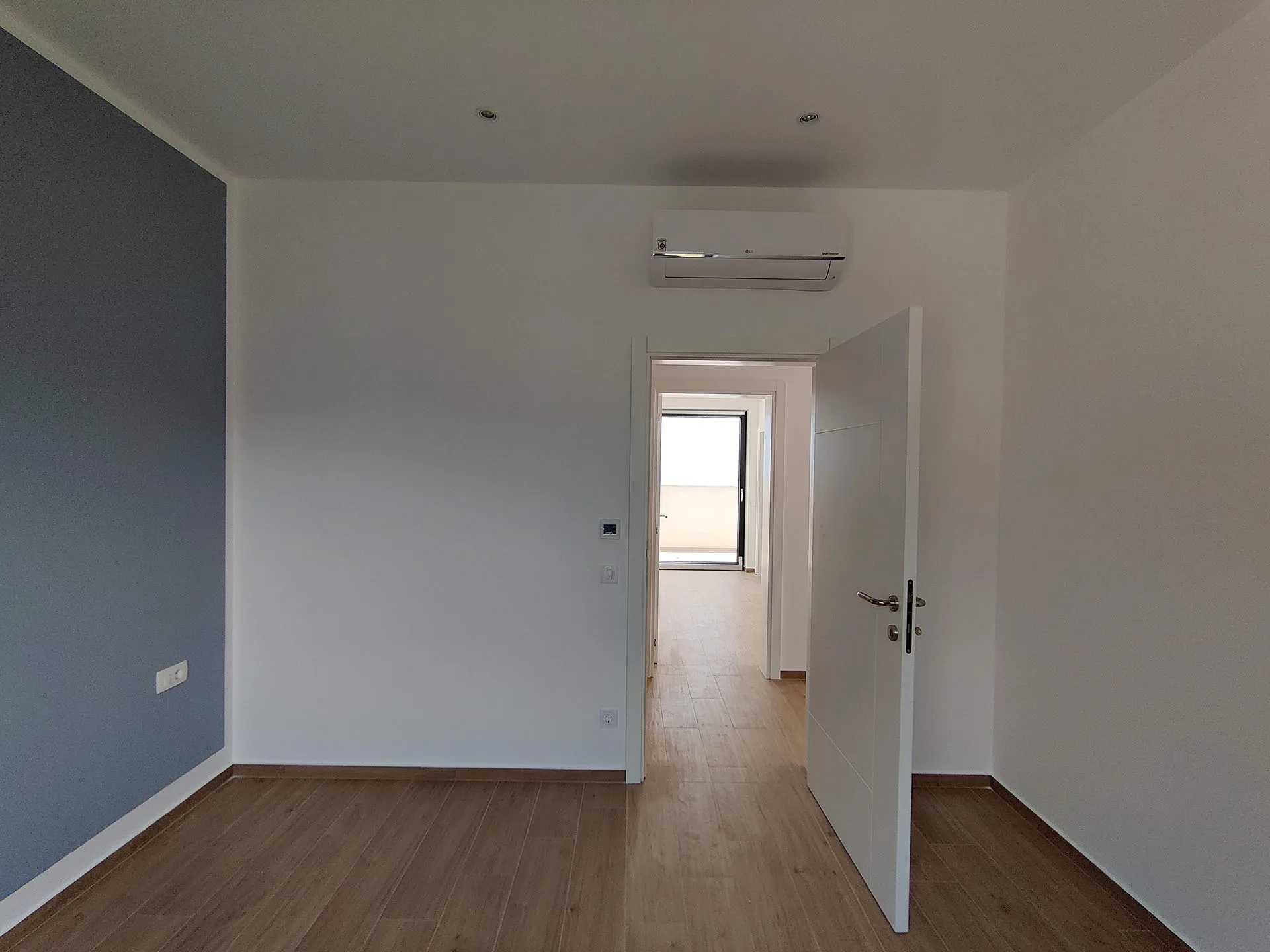 Helles Schlafzimmer in einer Wohnung, Becici, Montenegro: moderne Ausstattung, Laminat, Klimaanlage und Zugang zum Balkon.