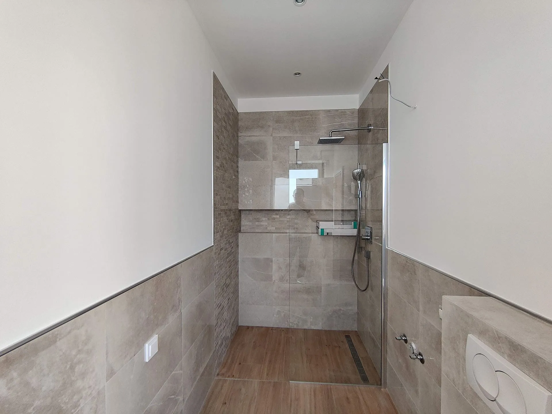 Modernes Badezimmer mit Duschkabine und Fliesenverkleidung in einer Wohnung in Bečići, Montenegro.