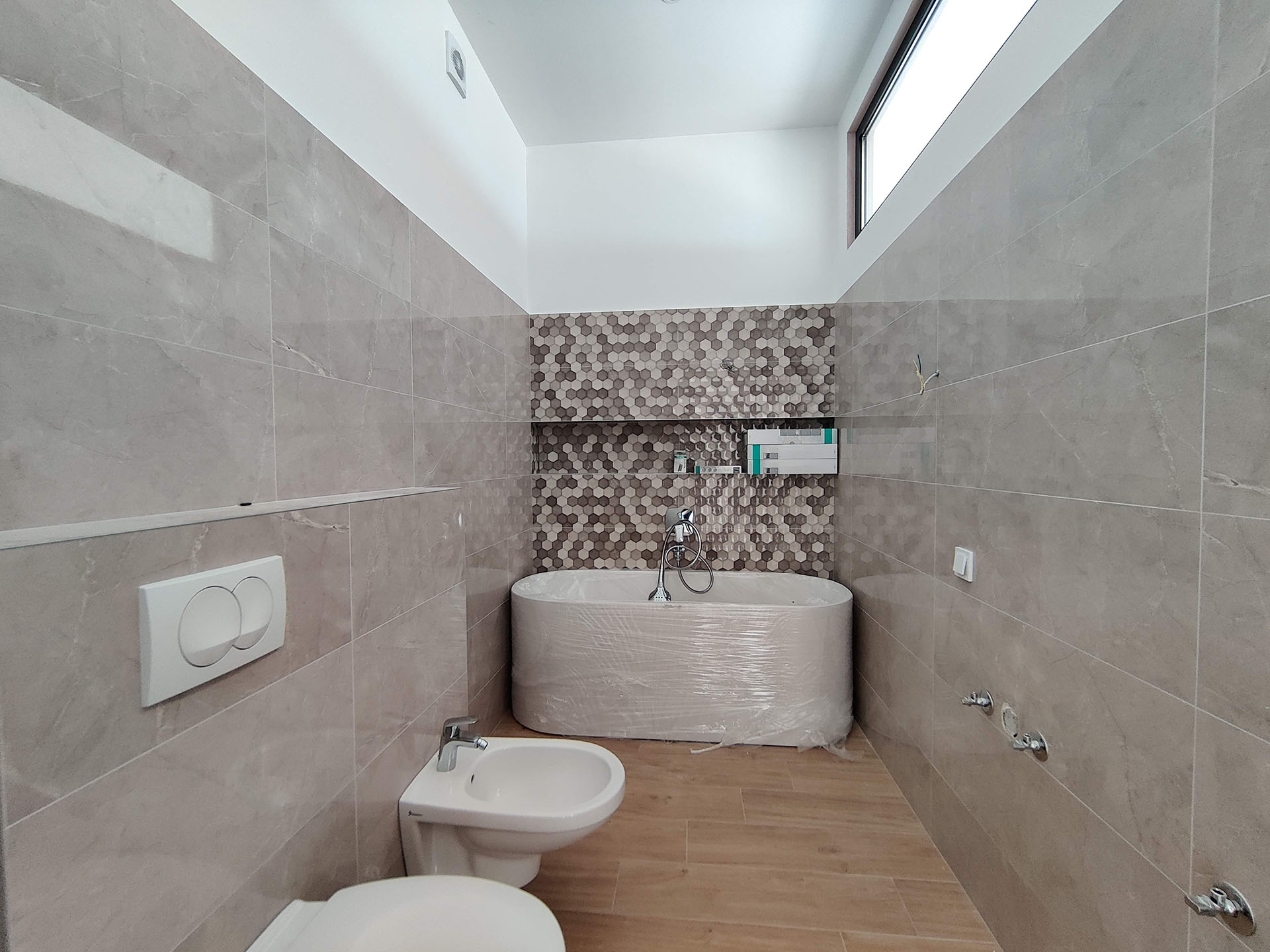Modern bathroom in an apartment in Bečići, Montenegro: new bathtub, bidet, marble-look tile finish and mosaic.