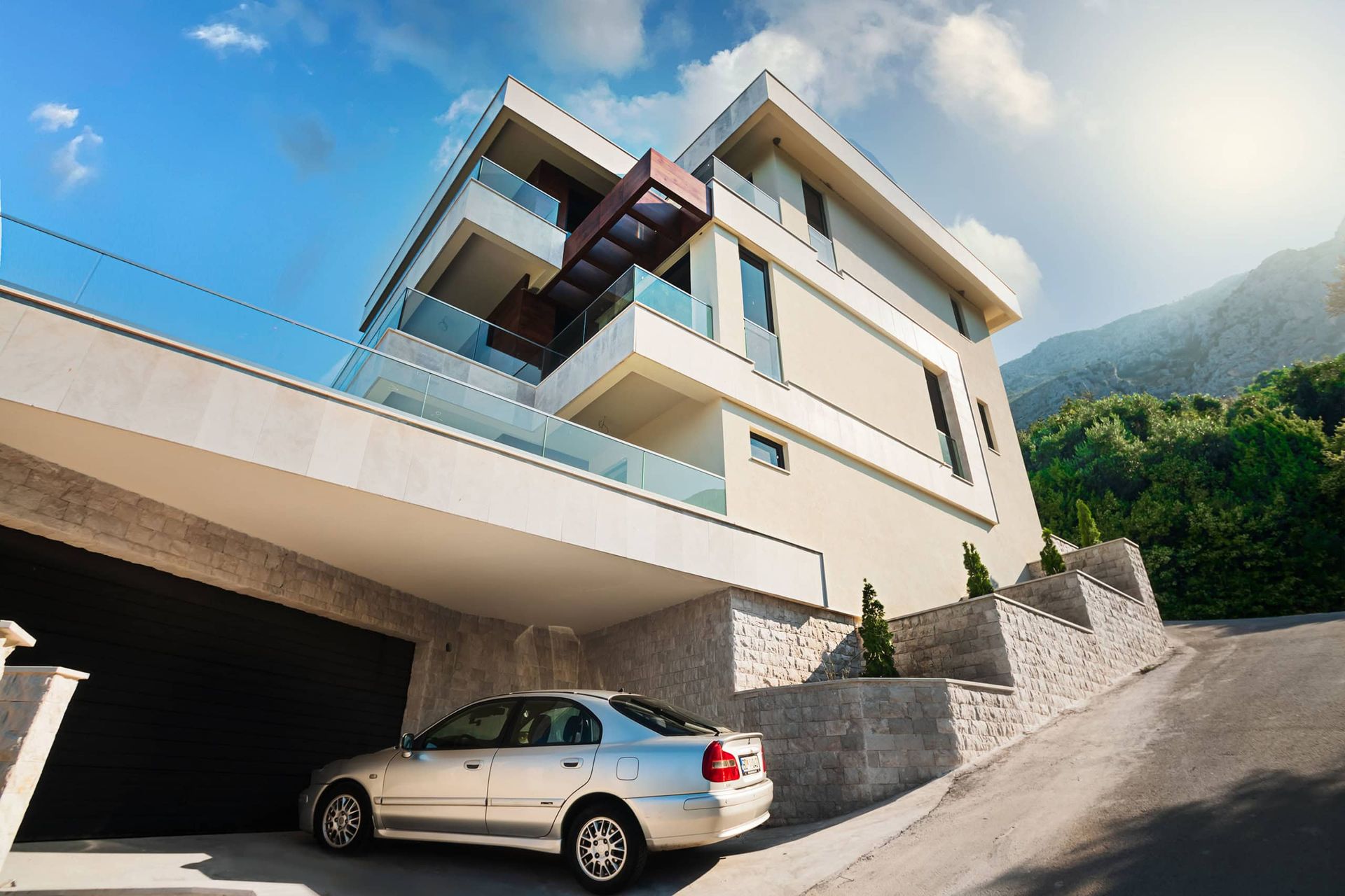 Karadağ, Drobni Pijesak’ta modern villa: teraslı cephe, taş kaplama ve dağlar fonunda garaj.