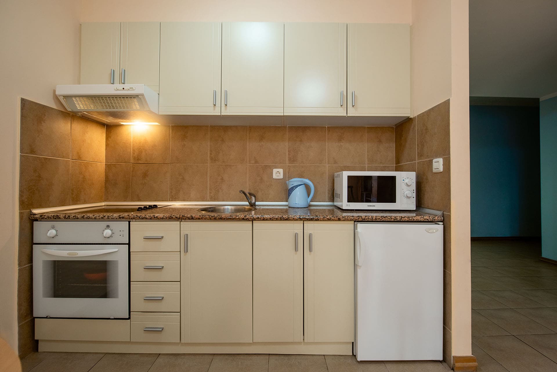 Kompakte Küche in einer Wohnung in Bečići, Montenegro: helle Einbauküche, integrierte Geräte, Herd und Mikrowelle.