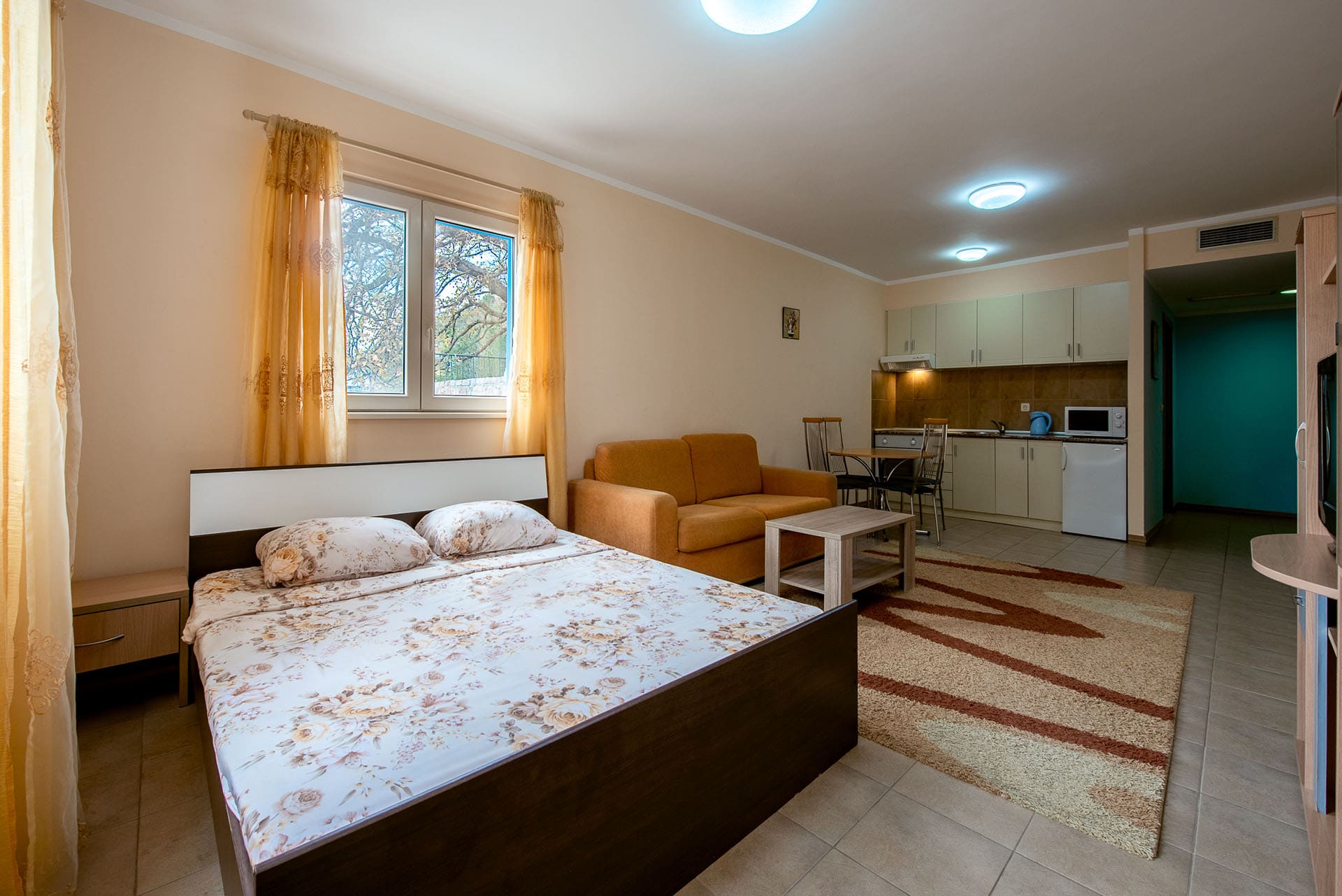 Innenraum des Wohnzimmers mit Doppelbett und Küche in einer Wohnung in Bečići, Montenegro: gemütliche Möbel und Blick aus dem Fenster.