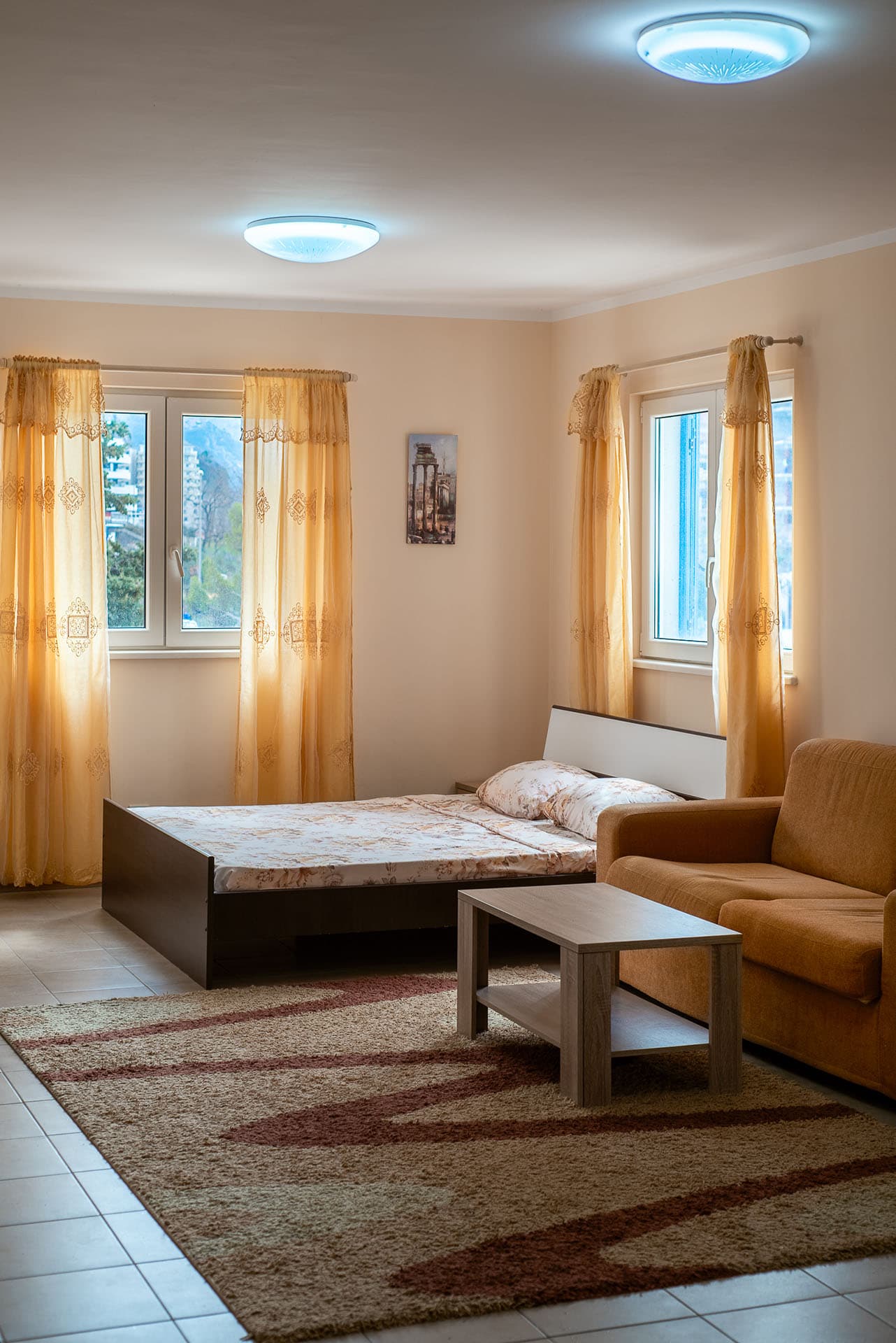 Schlafzimmer in einer Wohnung in Bečići, Montenegro: Doppelbett, weiches Sofa, Couchtisch und Blick aus dem Fenster.