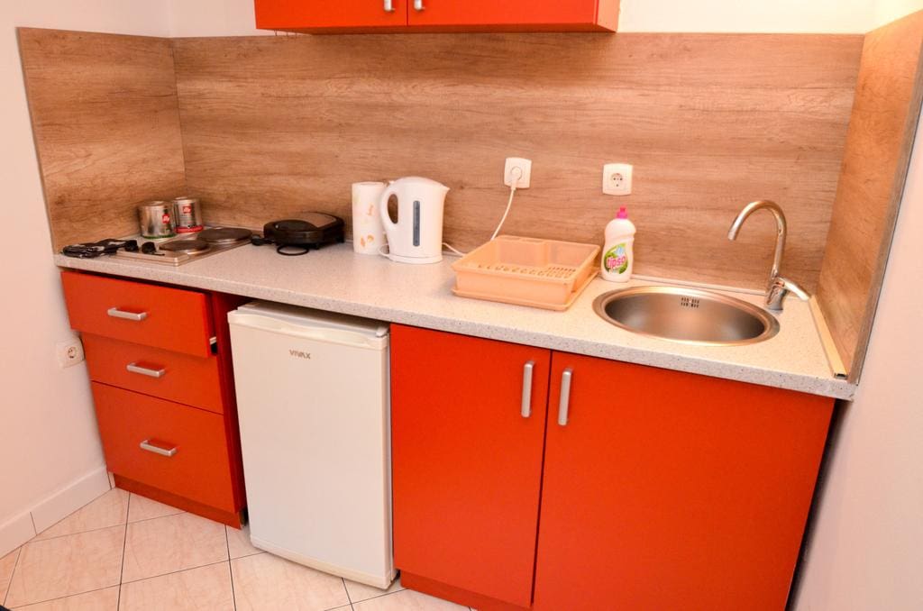 Kompakte Küche mit orangefarbenen Fronten und Geräten in den Apartments, Stadt Kotor, Montenegro.