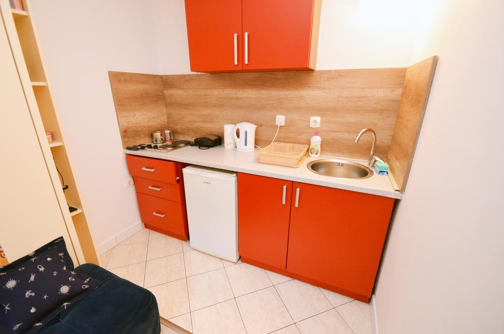 Kompakte Küche mit orangefarbenen Fronten und Einbaugeräten in den Apartments, Stadt Kotor, Montenegro.