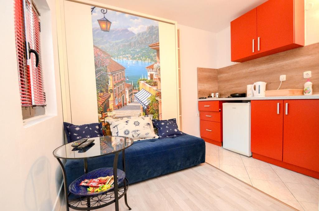 Wohnzimmer mit heller Küche und Sofa in einem Haus in Kotor, Montenegro: modernes Interieur mit Fototapete und Sitzecke.
